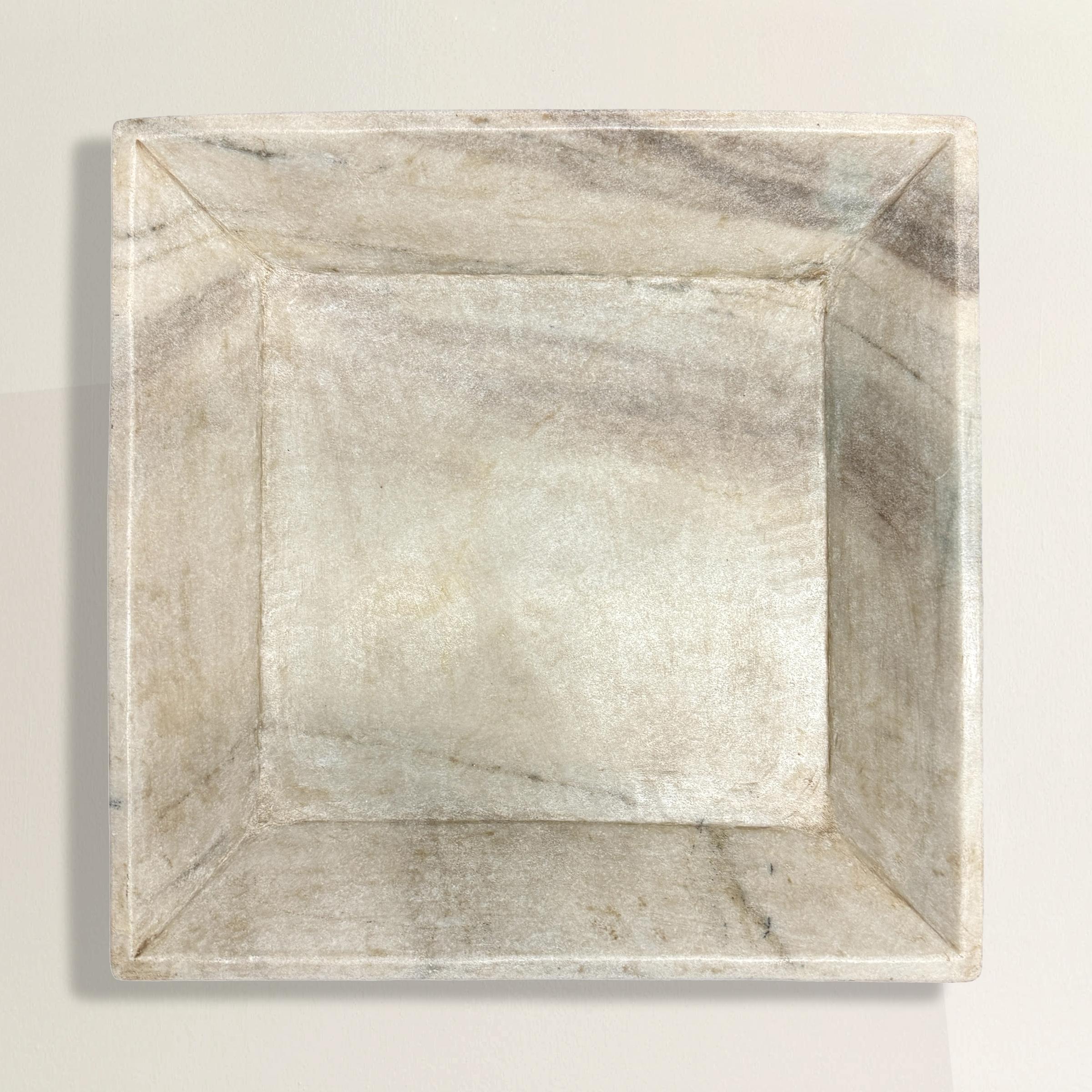 This rather large hand-carved white marble tray is a statement piece of exceptional beauty and craftsmanship. Its square form with tall tapered sides provides both elegance and practicality, while the wonderful beige and gray grain movement in the