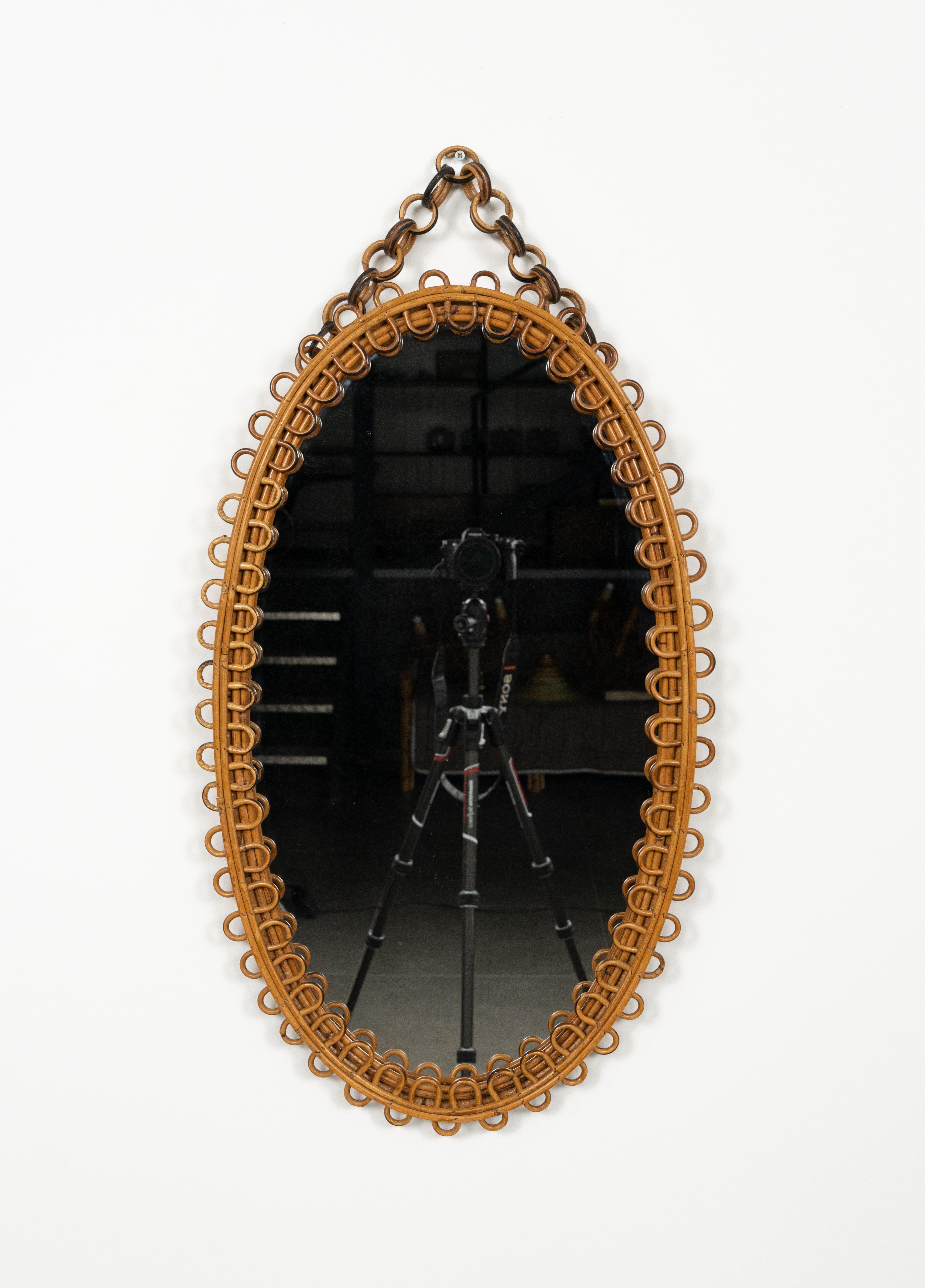 Midcentury beautiful oval wall mirror with chain in bamboo and rattan in the style of Italian design Franco Albini.  

Made in Italy in the 1960s.

Dimensions without chain:  
Height 78 cm.  
Width 46.5 cm. 
Depth 3.5 cm.
