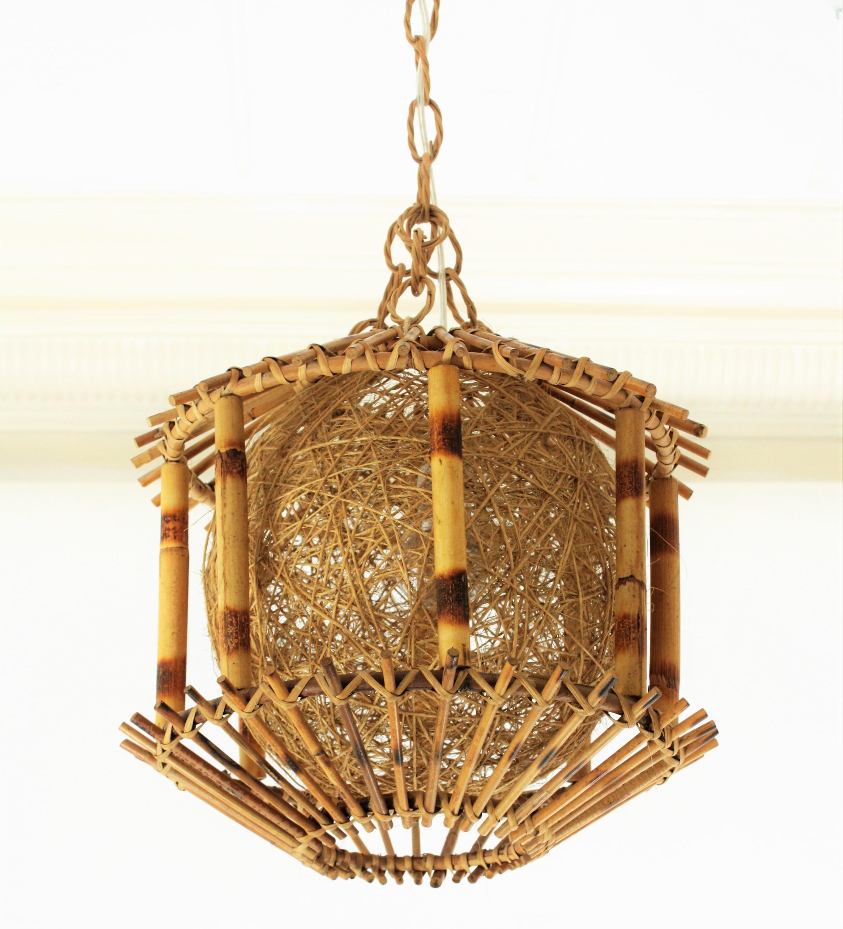 Unusual Spanish modernist bamboo and rattan pendant lamp or lantern with chinoiserie accents and a woven rope globe shade, Spain, 1950s.
This sculptural oriental inspired lamp is hanging from a rattan chain and it has a charming light when lit.