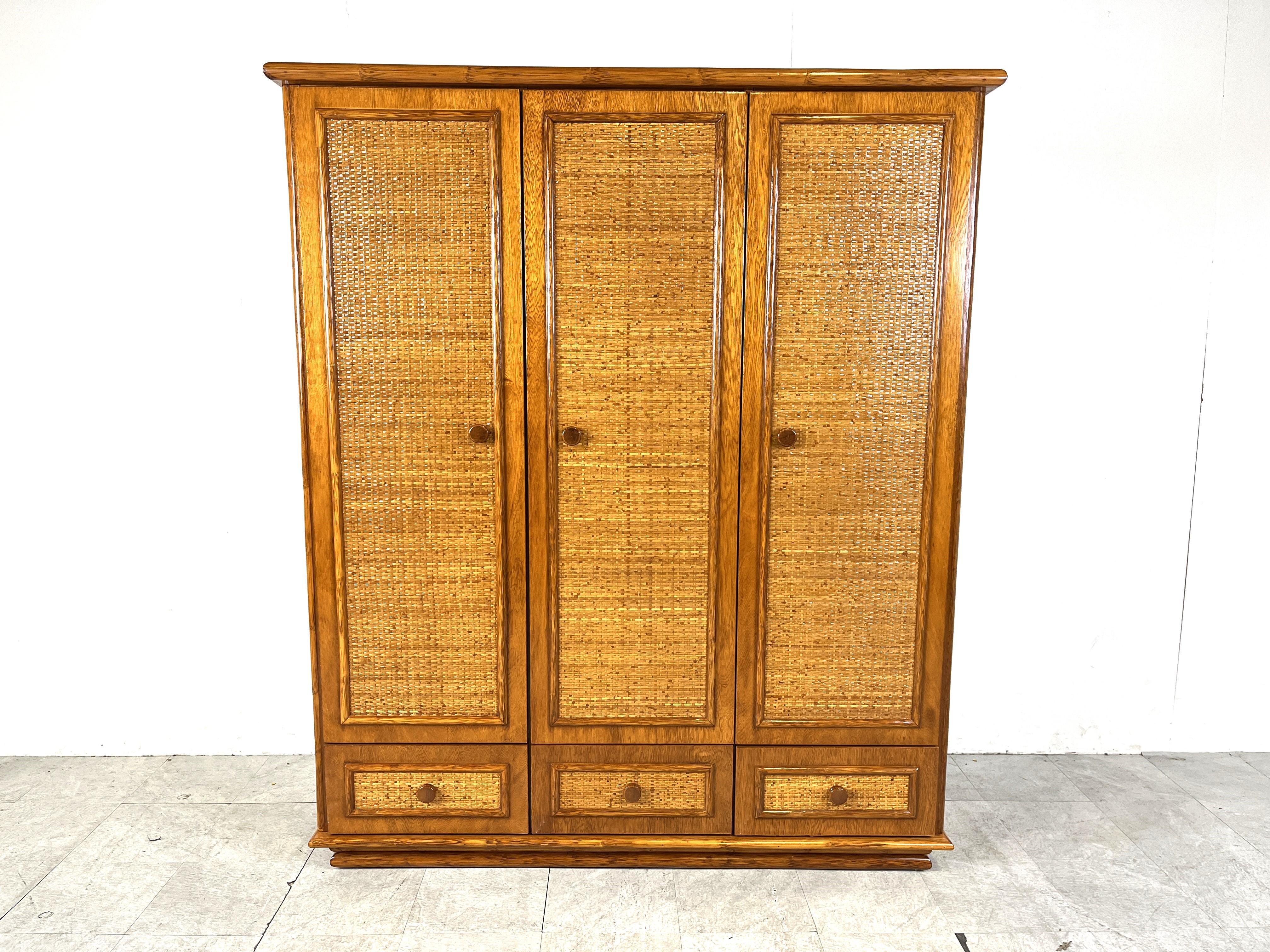 Vintage wardrobe by Maugrion and was sold back in the days in the high end furniture stores from Roche Bobois.

The wardrobe has 3 doors and  3 drawers and is made of wood, rattan and bamboo.

Very well made wardrobe which offers plenty of storage