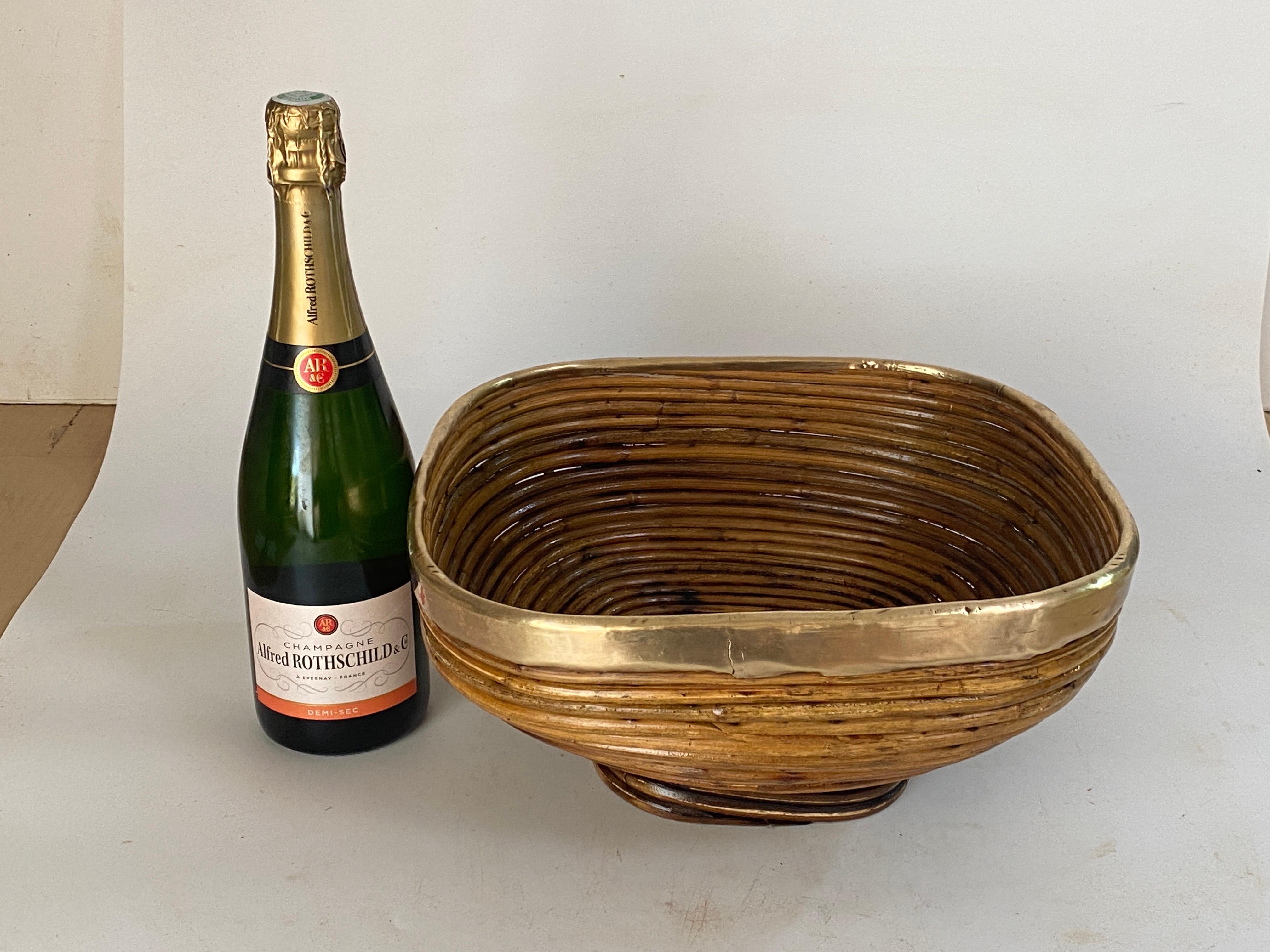 Mid-Century Modern brass and bamboo / rattan largebowl, centerpiece or basket.
It has a brass trim covering the top.
Handcrafted in Italy, 1970s. 
Use it as fruit bowl or centerpiece to add a stylish Midcentury accent in a kitchen. Perfect to
