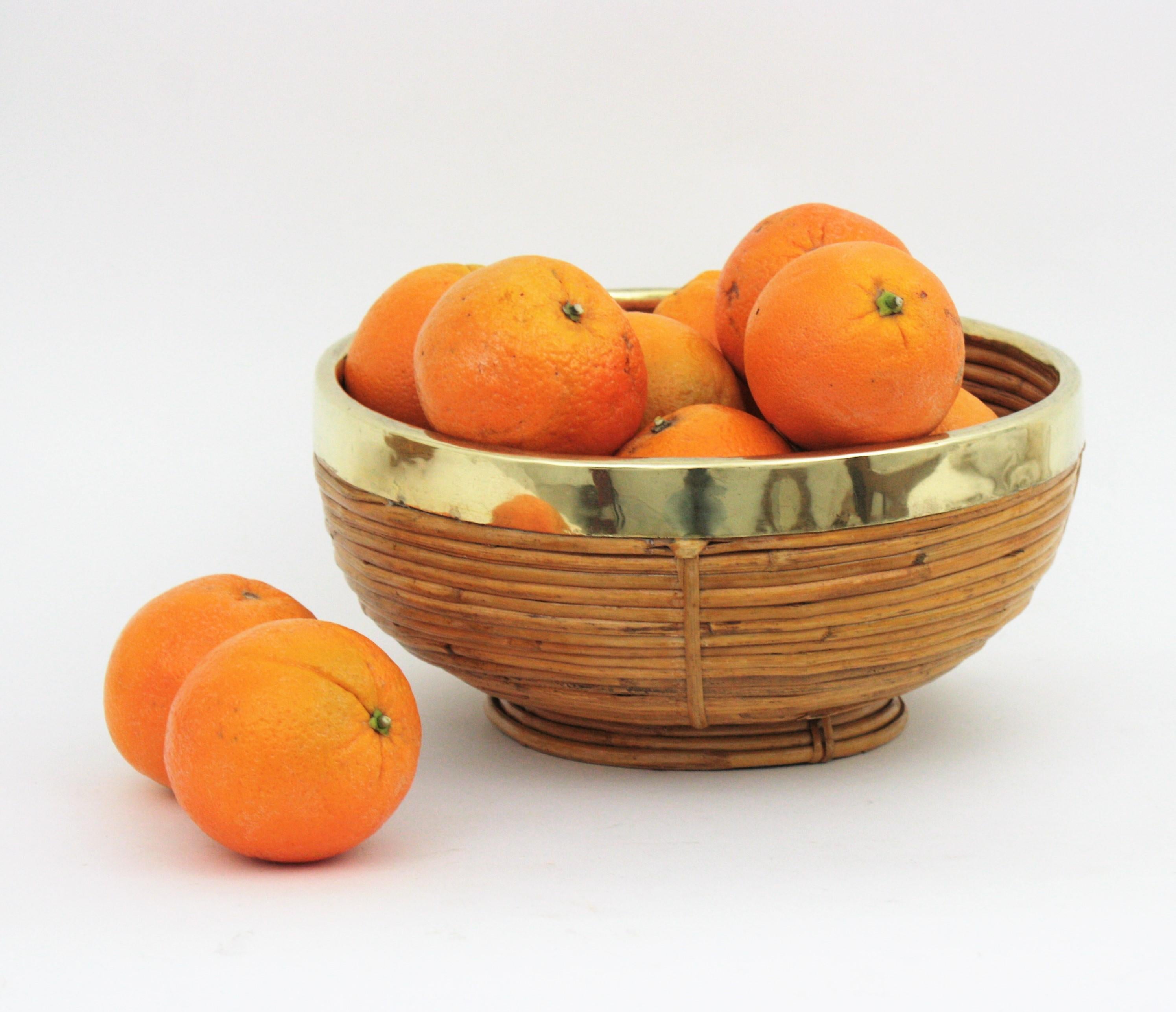 Mid-Century Modern brass and bamboo / rattan large bowl, centerpiece or basket.
It has a brass trim covering the top.
Handcrafted in Italy, 1970s. 
Use it as fruit bowl or centerpiece to add a stylish Midcentury accent in a kitchen. Perfect to