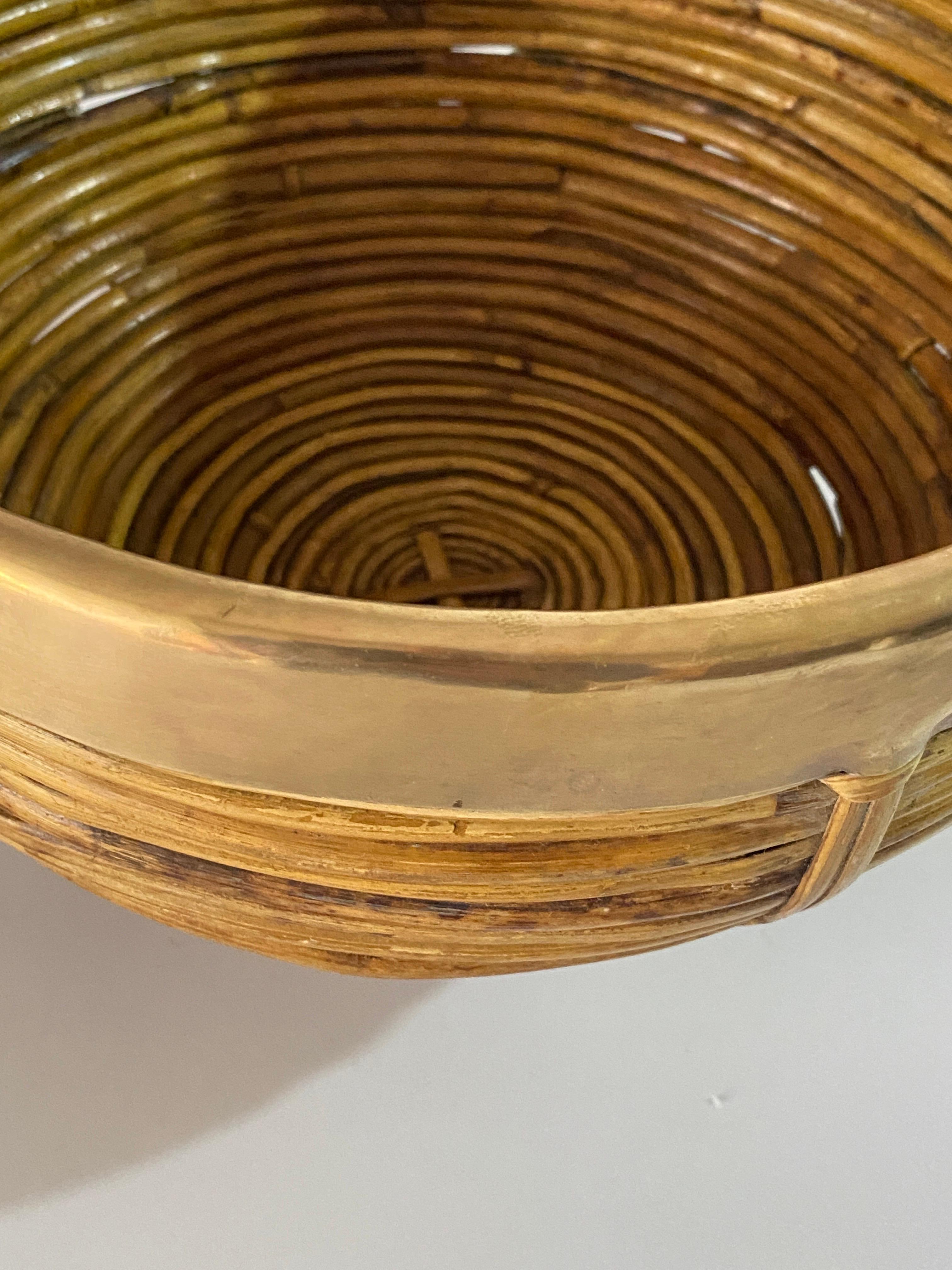 Mid-Century Modern brass and bamboo / rattan large oval bowl, centerpiece or basket.
It has a brass trim covering the top.
Handcrafted in Italy, 1970s. 
Use it as fruit bowl or centerpiece to add a stylish Midcentury accent in a kitchen. Perfect to