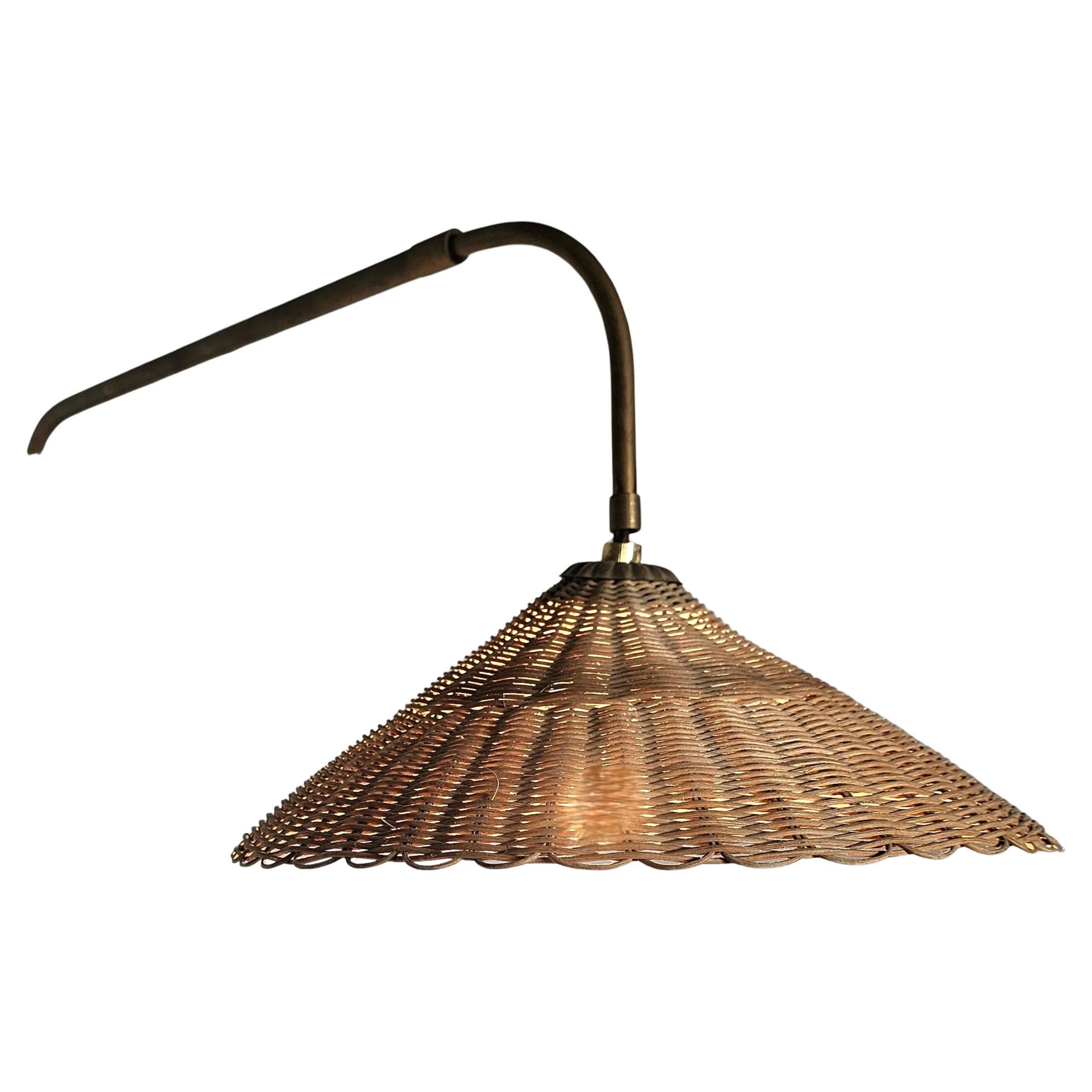 Rattan and Brass Wall Lamp in the Manner of Paavo Tynell, 1950s

Executed in woven rattan with an elegant slim brass wall mounted stem, this plug-in sconce brings warmth and refinement to any space. 

The woven rattan lamp shade cast a warm, ambient