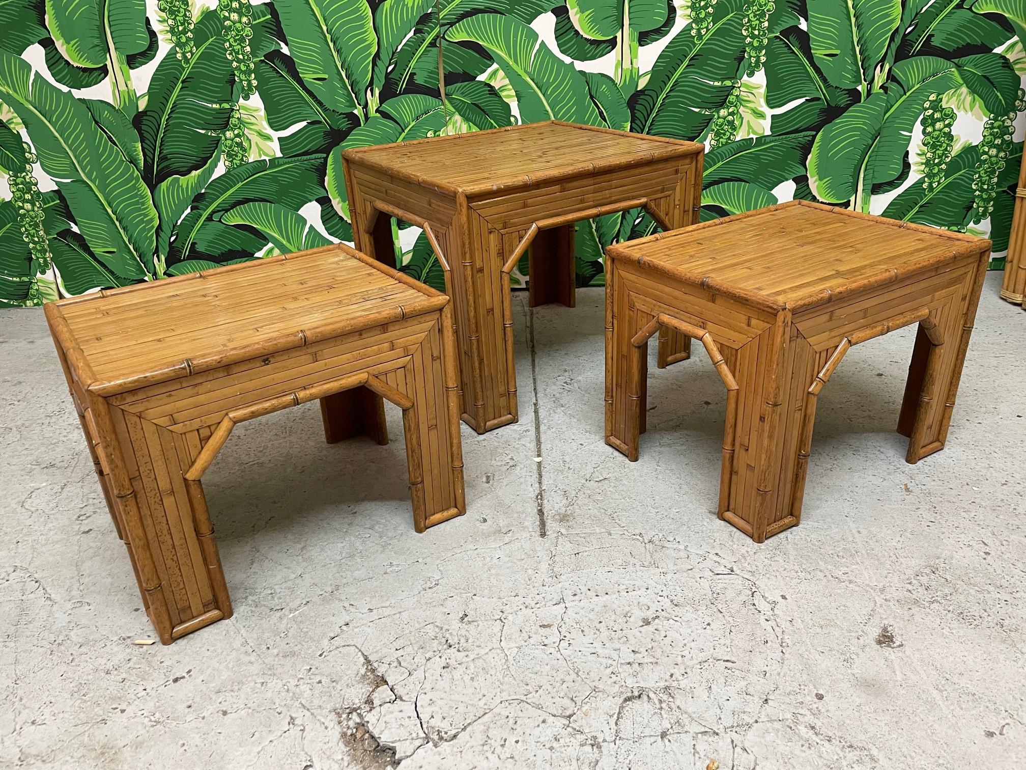 Set of 3 vintage side tables feature full veneer of split reed rattan and faux bamboo detailing. Two smaller matching tables measure 20
