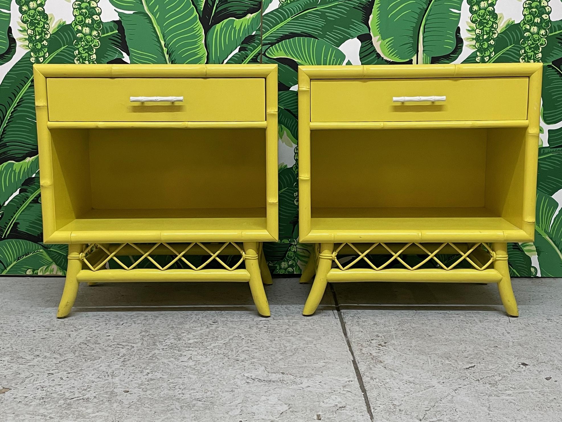 Pair of vintage faux bamboo nightstands feature rattan fretwork and splayed legs. Bright yellow lacquered finish. Good condition with minor imperfections consistent with age.