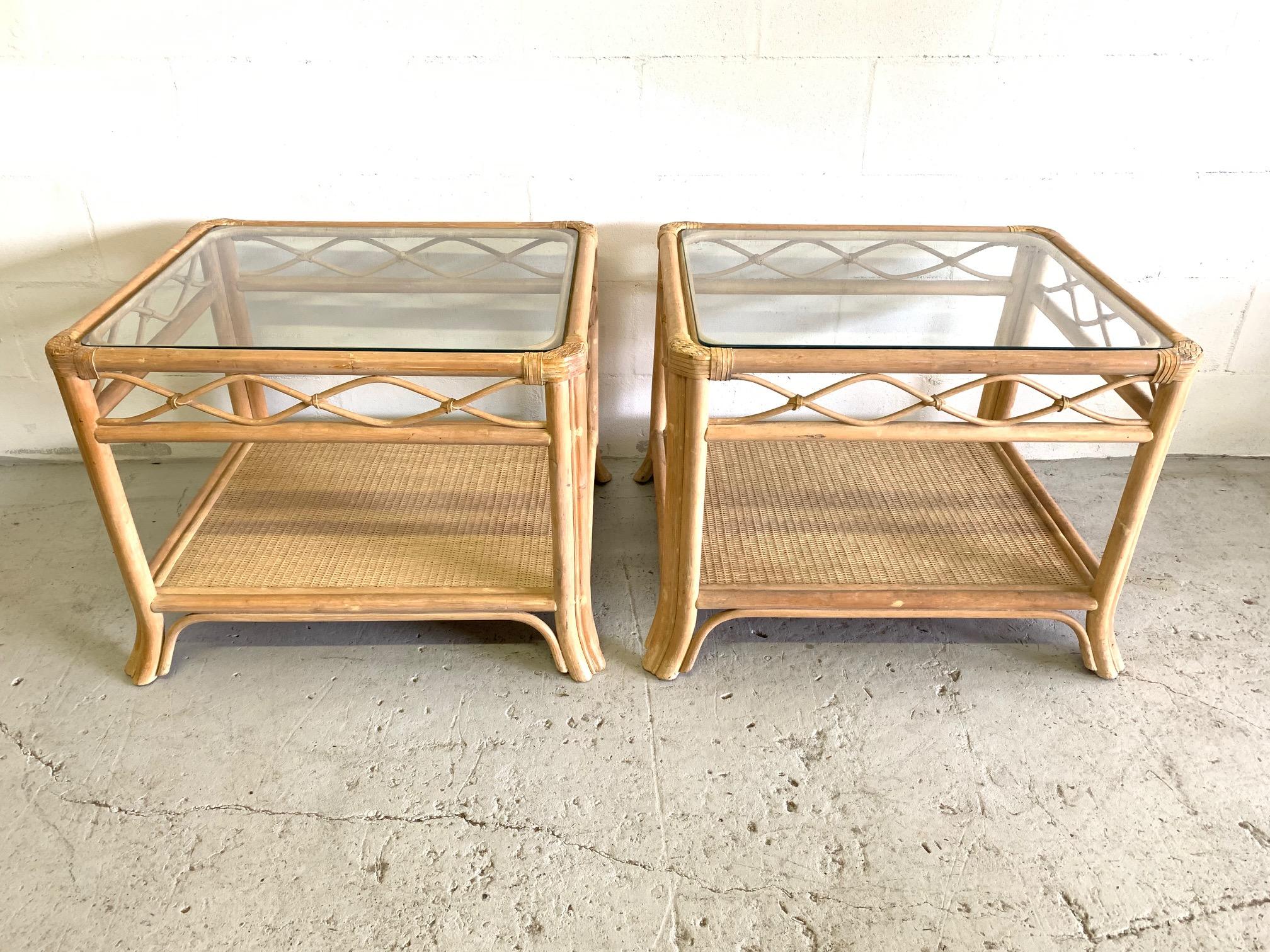 Pair of rattan end tables feature glass top woven wicker lower shelf. Perfect touch of island style to any decor. Good condition with minor imperfections consistent with age.