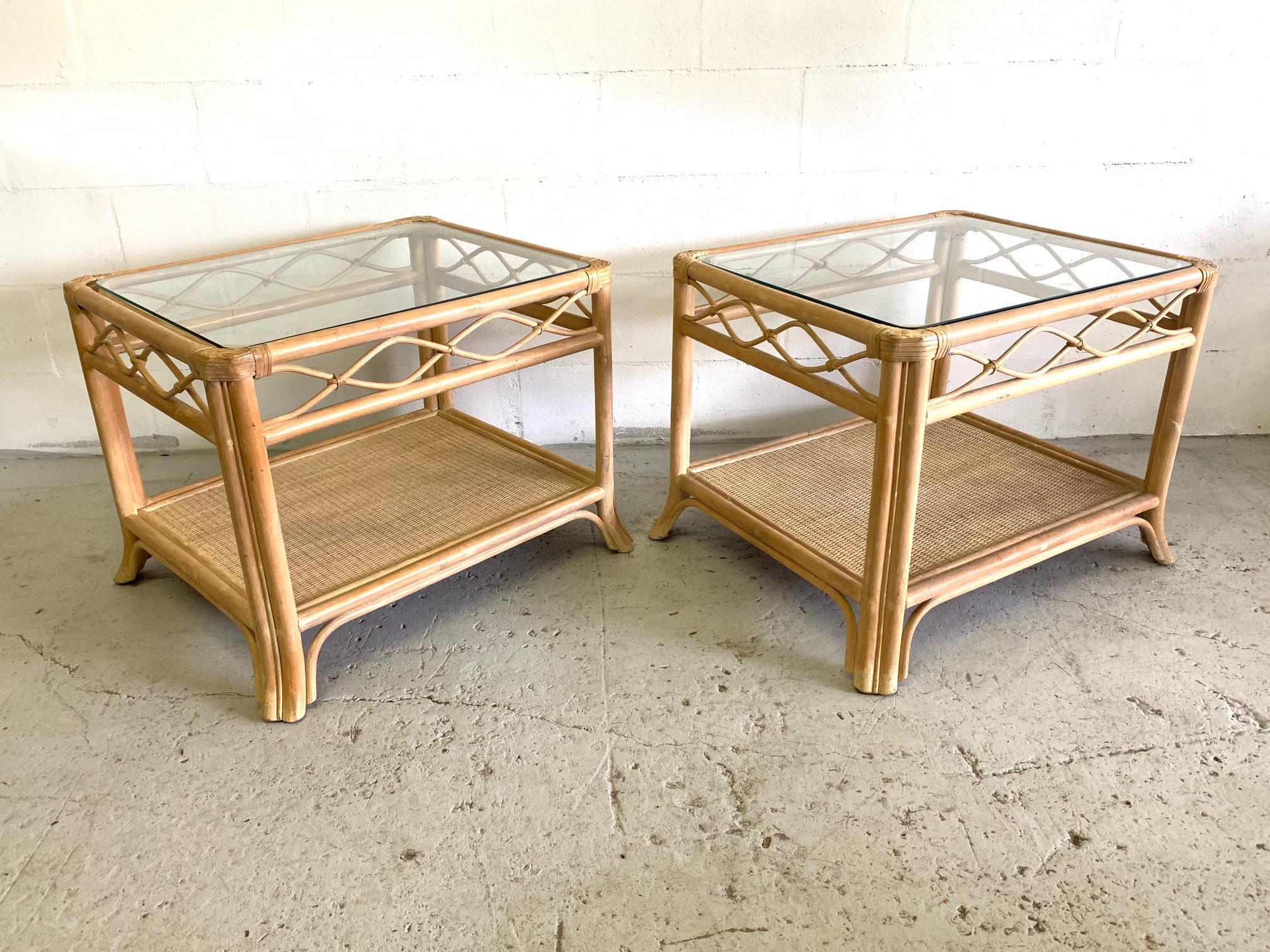 Pair of rattan end tables feature glass top woven wicker lower shelf. Perfect touch of island style to any decor. Good condition with minor imperfections consistent with age.
  
 