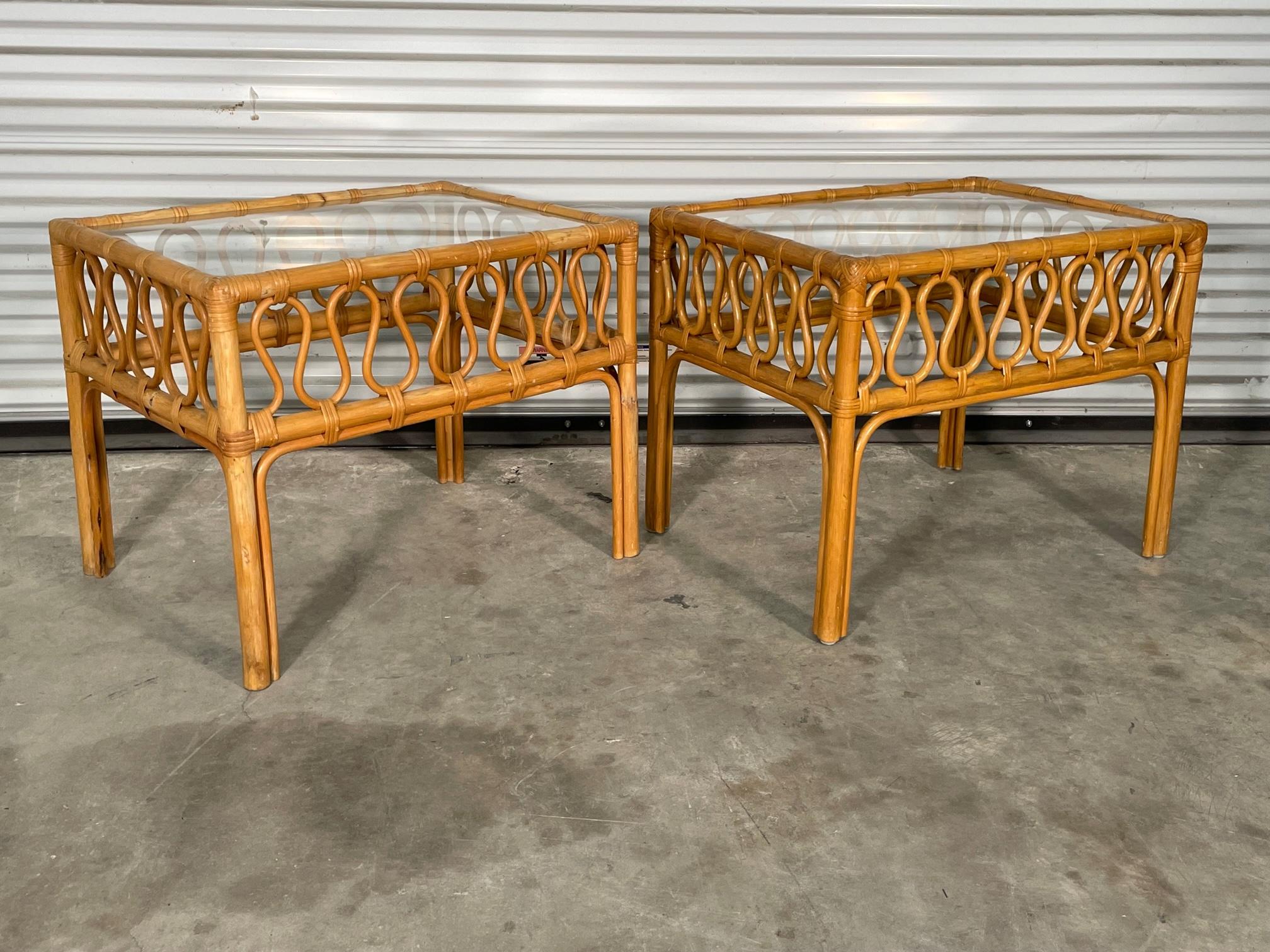 Pair of vintage rattan side tables feature a unique loop style fretwork and glass tops. Marked 