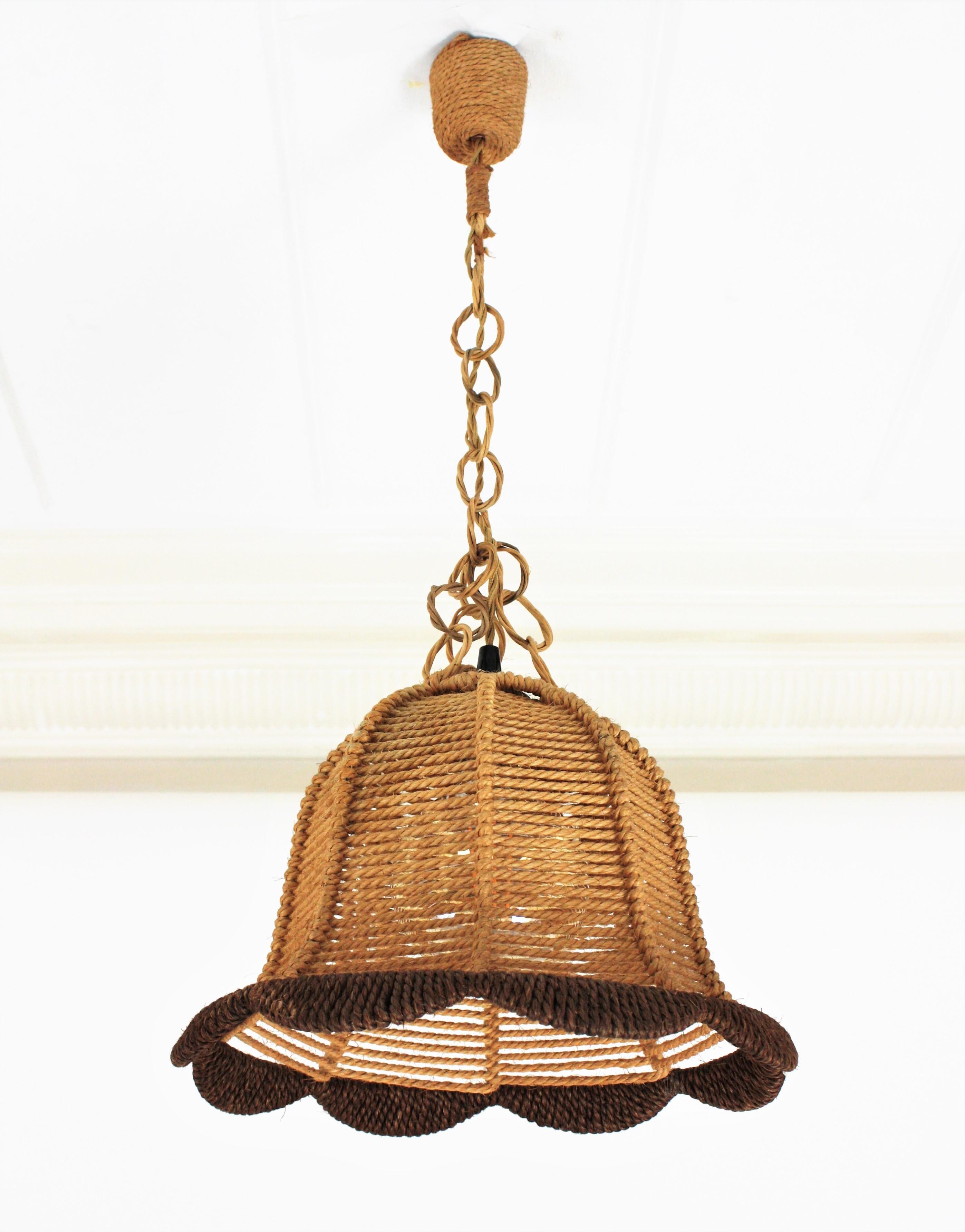 Eye-catching vintage bell shaped rope pendant light or lanternwith rattan chain, Spain, 1960s.
This midcentury suspension lamp features a bell shaped rope covered lampshade combining beige and brown rope. It hangs from a chain with rattan links
