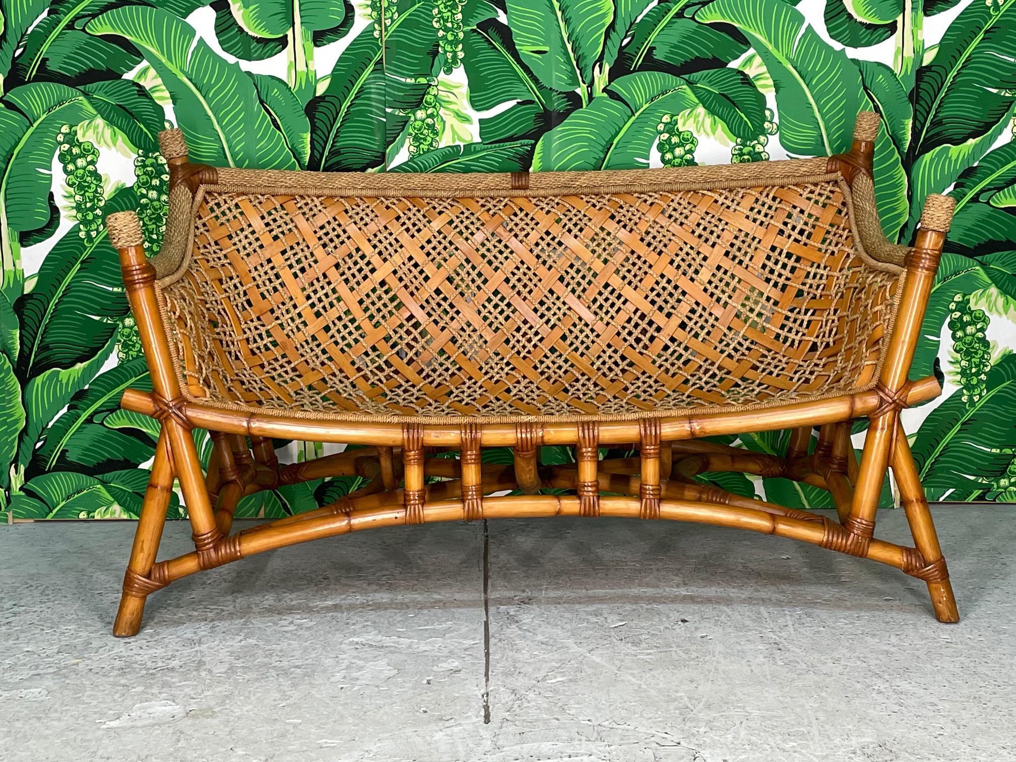 Unique vintage rattan bench sofa features a sling seat design and woven rope and reed detailing. Chinoiserie influence with it's pagoda style base and flared legs. Excellent condition with only very minor imperfections consistent with age.

 