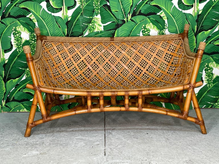 Unique vintage rattan bench sofa features a sling seat design and woven rope and reed detailing. Chinoiserie influence with it's pagoda style base and flared legs. Good condition with imperfections consistent with age. May exhibit scuffs, marks, or