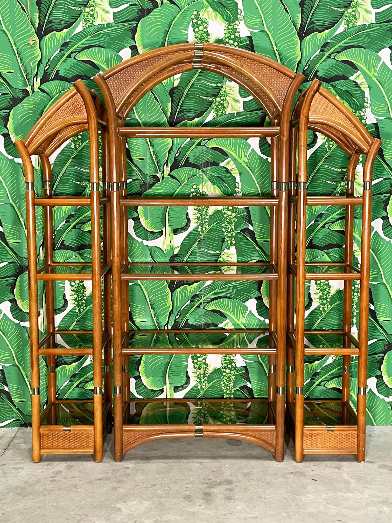 Mid century rattan wall unit or bookshelves feature wicker veneered arched tops and campaign style brass accents. Shelves are smoked glass. Good condition with imperfections consistent with age, see photos for condition details.
For a shipping quote