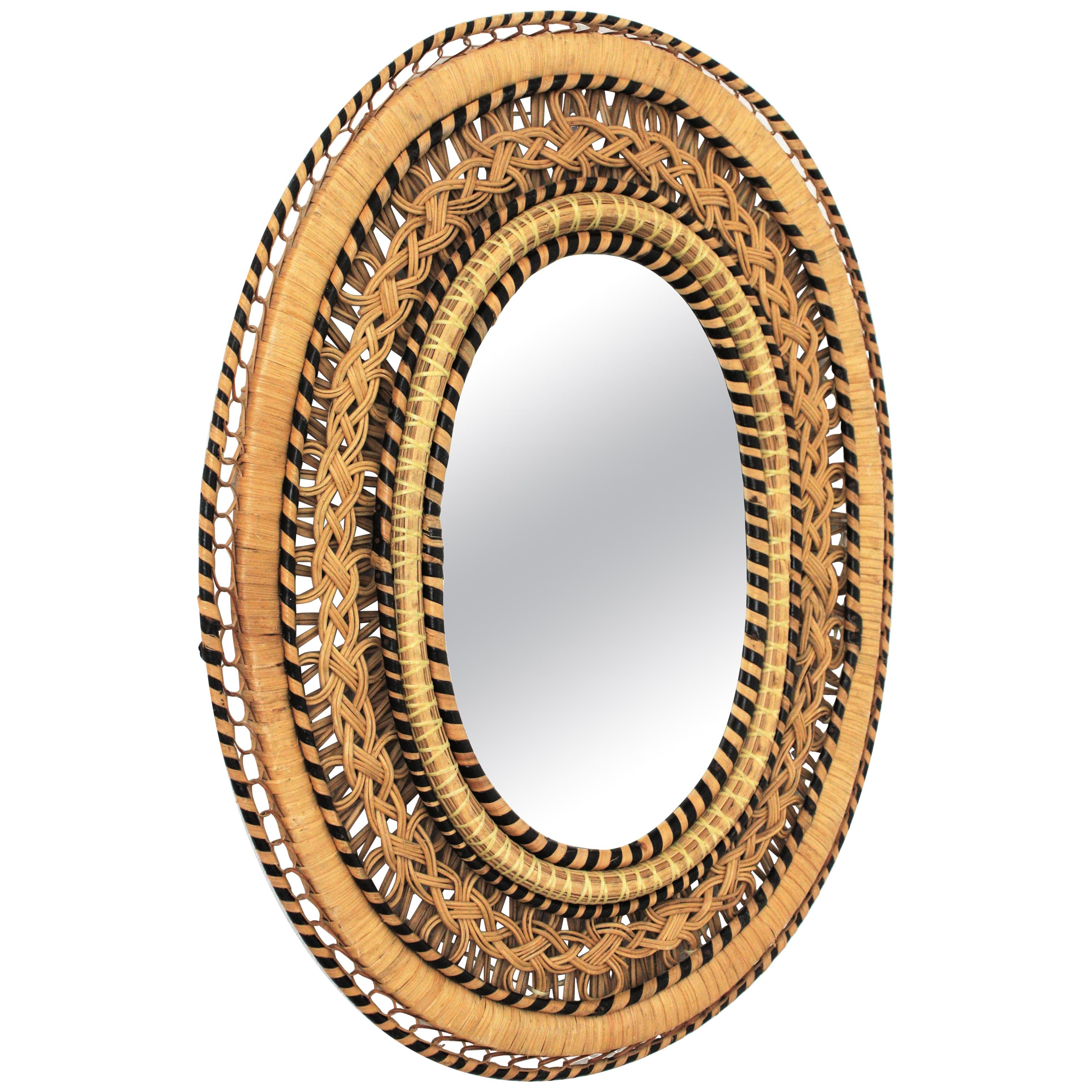 Spanish woven wicker and rattan oval shaped mirror, Spain, 1960s-1970s.
This mirror has an amazing handcrafted woven work combining nude color and black color creating a beautiful visual effect. Woven in the manner of the Emmanuelle Peacock