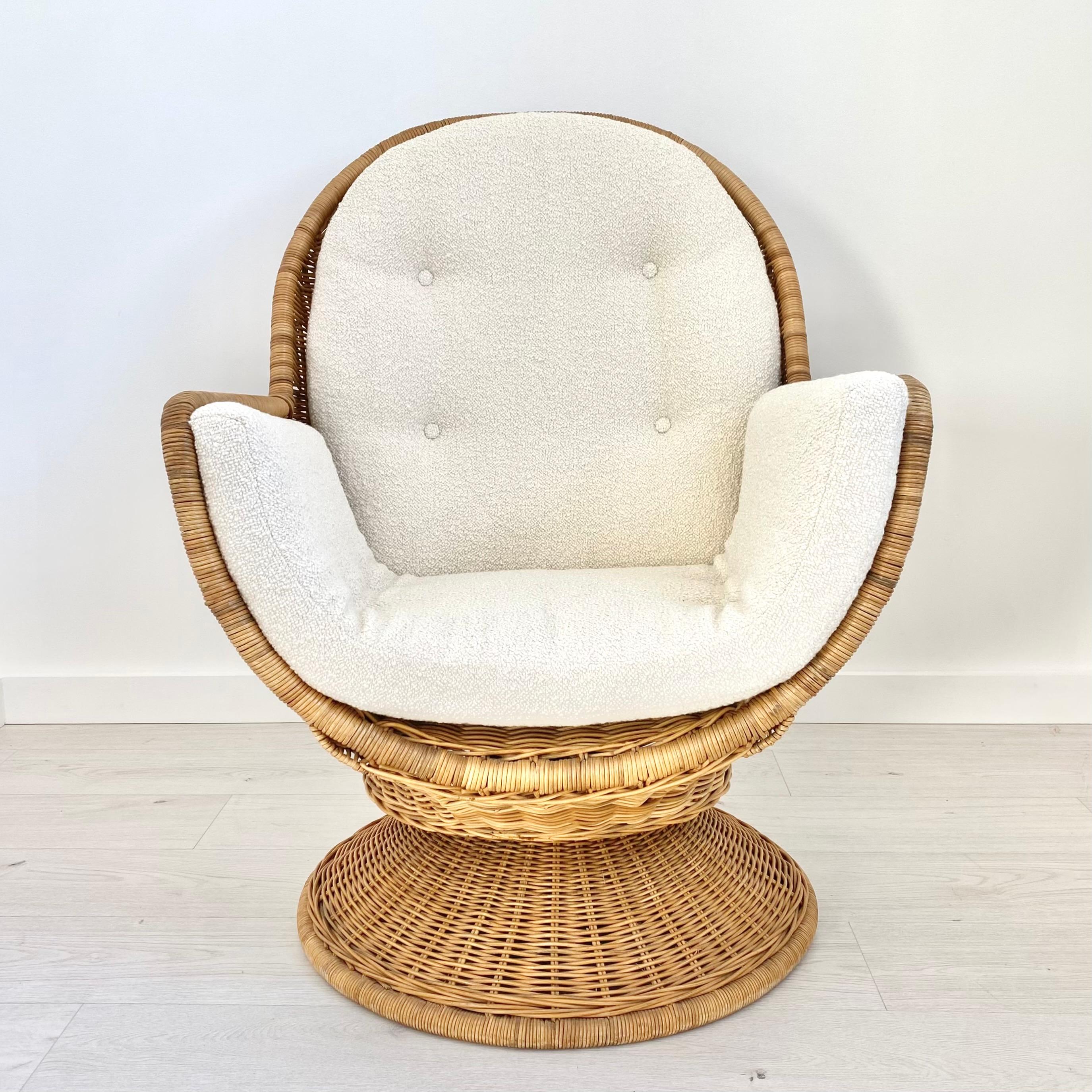 Beautiful egg-shaped rattan and wicker chair from the 1970s. Original cushions newly reupholstered in white wool boucle. Chair swivels 360 degrees and tilts backwards. Incredibly unique design. Perfect accent piece for a touch of warmth and fun in