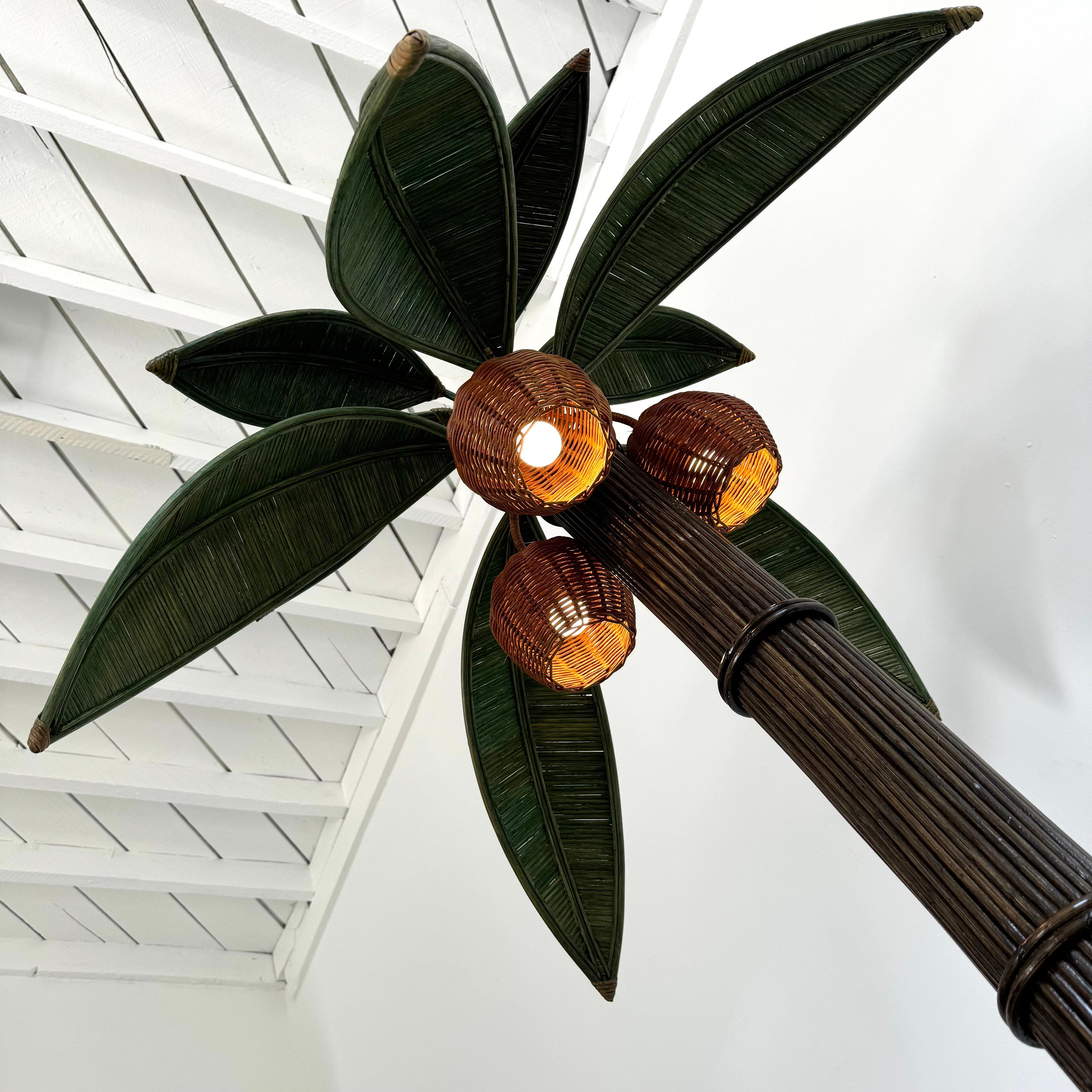 Beachy floor lamp of a palm tree. Original lamp made in the 1970s. Just under 7 feet tall. Made of rattan and wicker and darkened bamboo. Curved trunk resembles a leaning palm tree. Three wicker coconuts each contain a socket/light inside. Coconuts