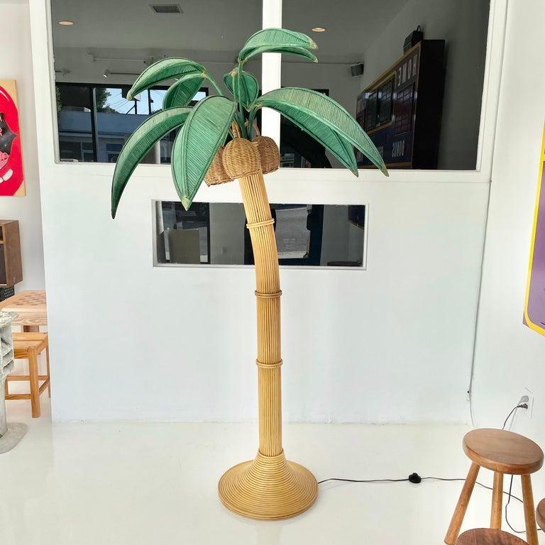Lampadaire de plage représentant un palmier. Un peu moins de 2 mètres de haut. Fabriqué en rotin et en osier. Trois noix de coco en osier contiennent chacune une douille/lampe à l'intérieur. Les noix de coco pivotent. Des feuilles de palmier vertes