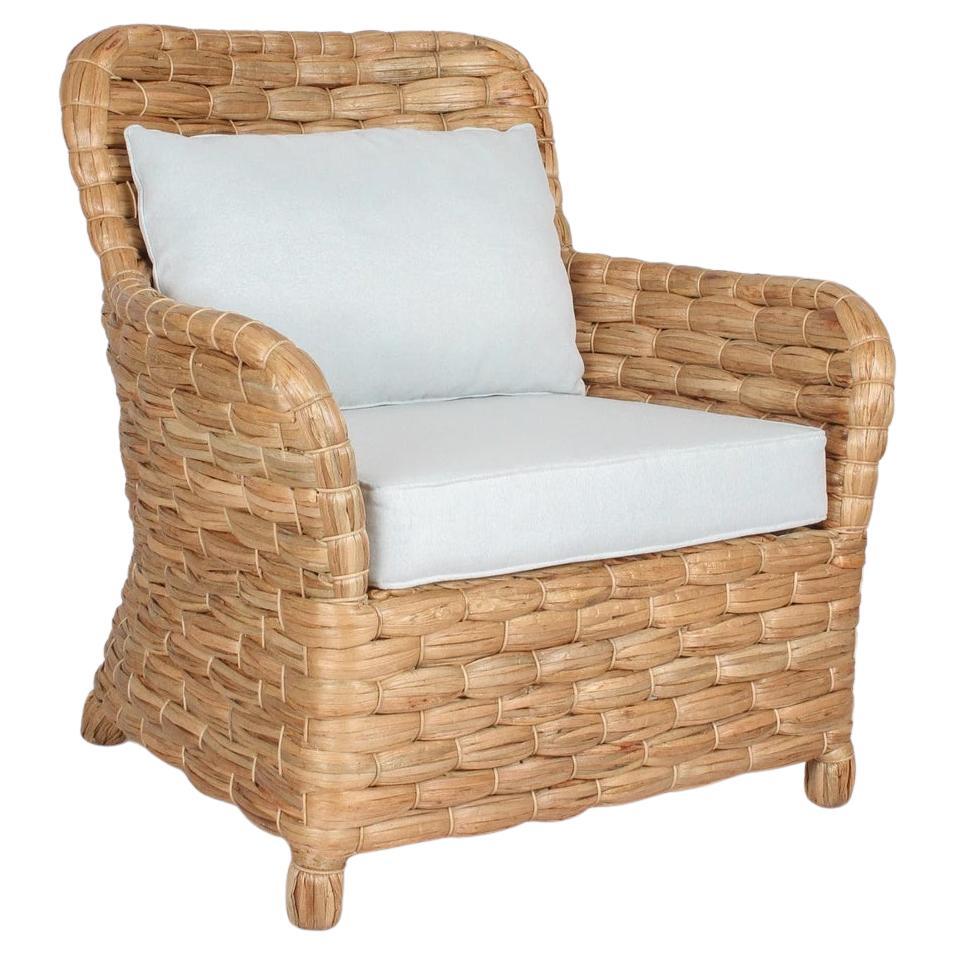 Fauteuil en rotin avec dossier droit et coussin en ton blanc