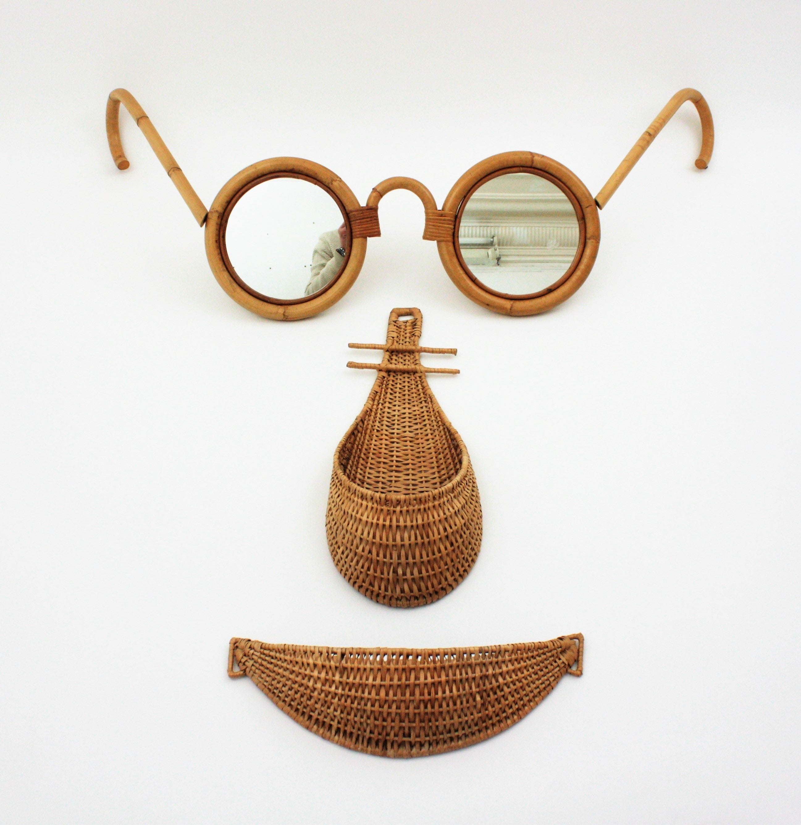 One of a kind giant eyeglasses face wall art / wall decoration, Spain, 1960-1970.
This eye-catching wall composition features giant bamboo glasses with mirrors and two wicker baskets as nose and mouth.
The eyeglasses sculpture are shaped in a