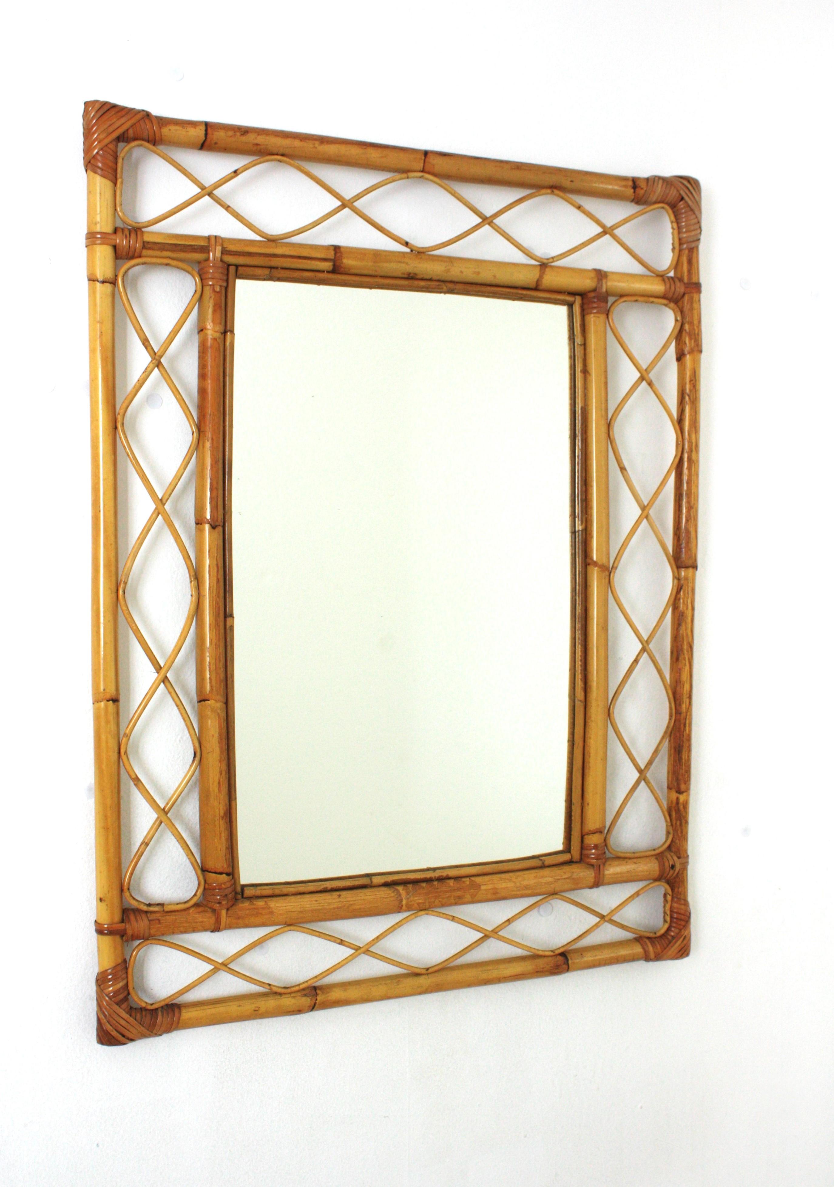Miroir en bambou et en rotin fabriqué à la main, de style Franco Albini, qui attire le regard. Italie, années 1960.
Ce miroir présente un double cadre rectangulaire en bambou avec des ondulations décoratives en rotin entre les cannes de bambou.
Ce
