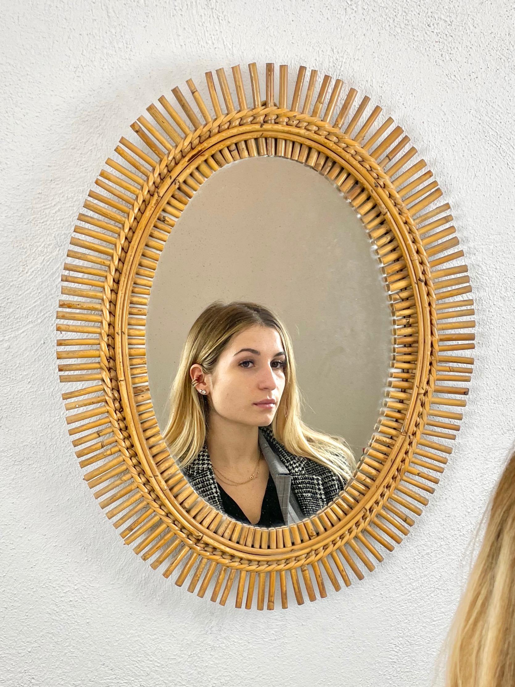 Oval wall mirror with rattan bamboo frame made in Italy in the 1960s. The mirror presents beautiful homogeneous spots due to its age.