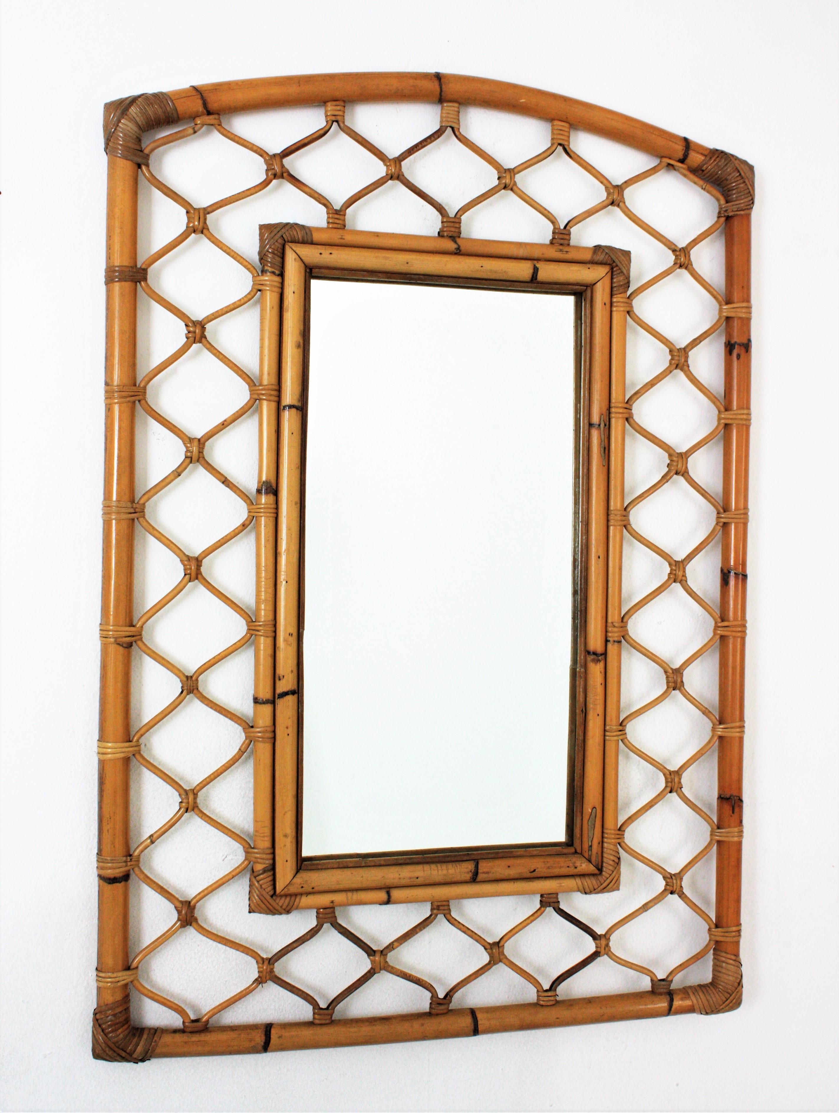 Eye-catching mid-century rectangular mirror with rattan bamboo frame. Spain, 1960s.
This Mediterranean wall mirror has a highly decorative frame made of two concentric rectangular bamboo frames with a rattan grid decoration between them. It has