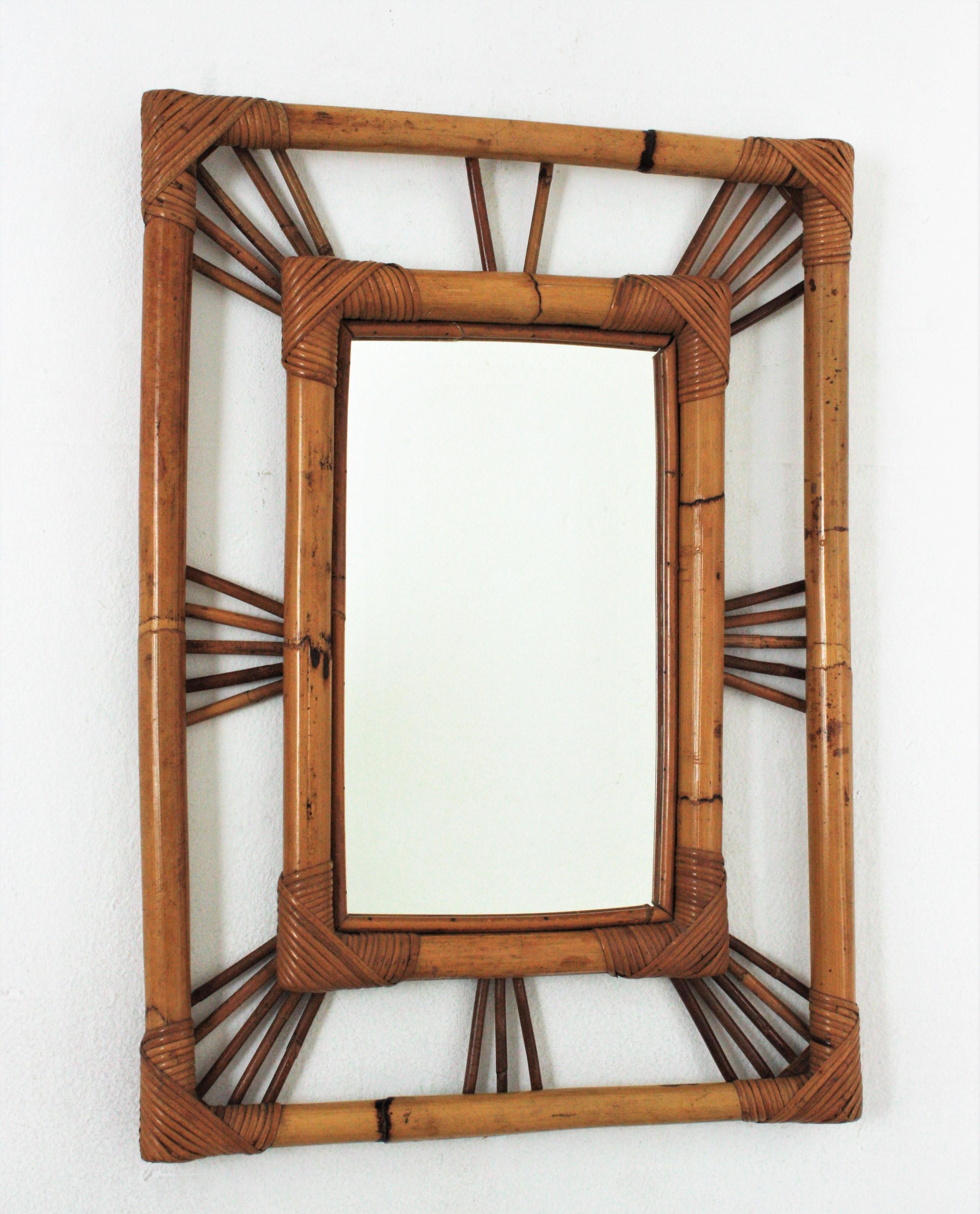 Eye-catching French Riviera rectangular mirror in rattan and bamboo. France, 1960s.
This wall mirror features a bamboo double frame surrounding a central glass. Rattan canes in sunburst disposition joining the bamboo frames.
This piece has all the