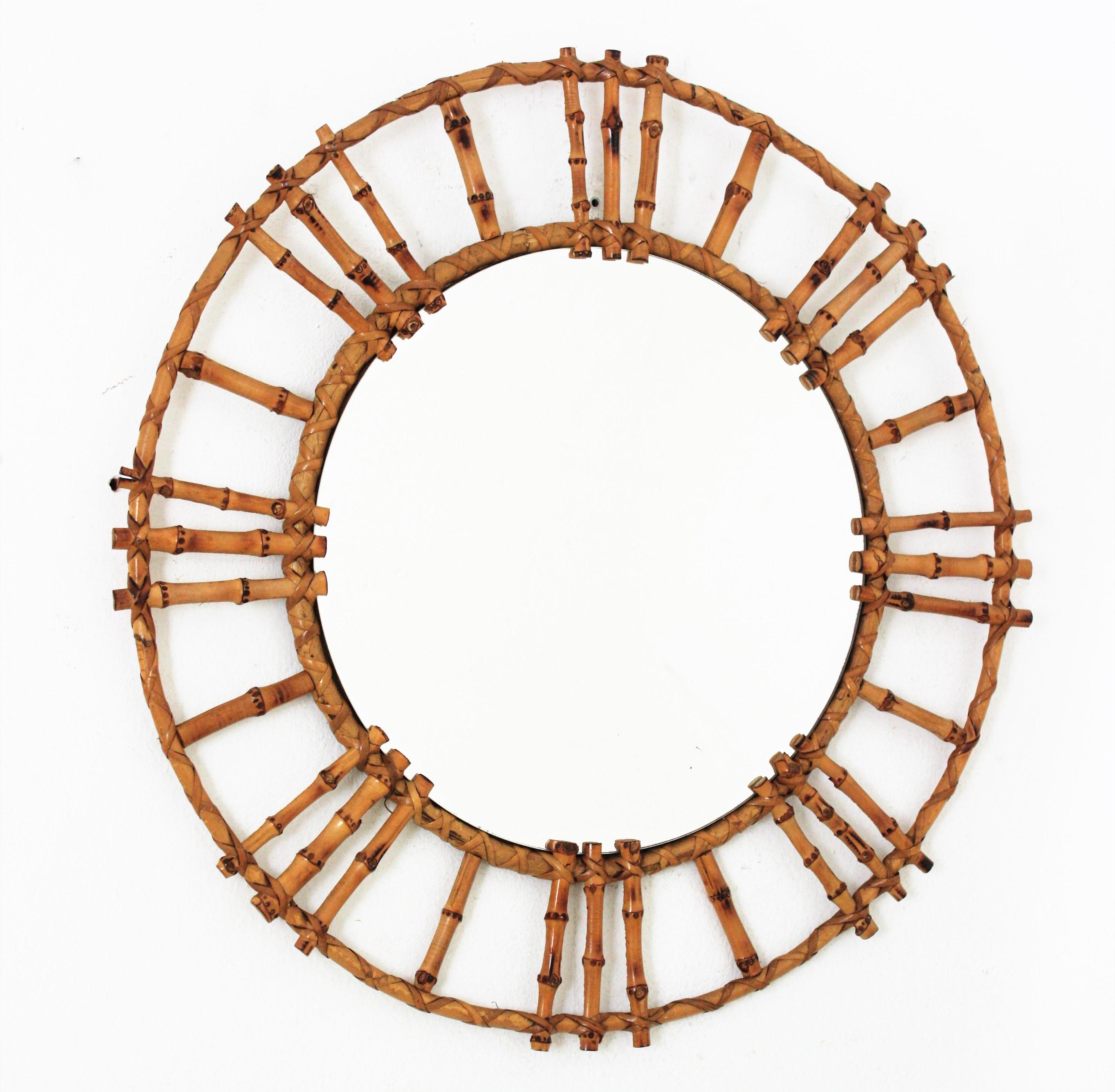 Spanish bamboo rattan round sunburst mirror, 1950s.
Handcrafted wall mirror with rattan and bamboo frame. It has a nice design with Tiki style reminiscences. 
This mirror will add a fresh Midcentury but Tiki accent to any interior decoration.
