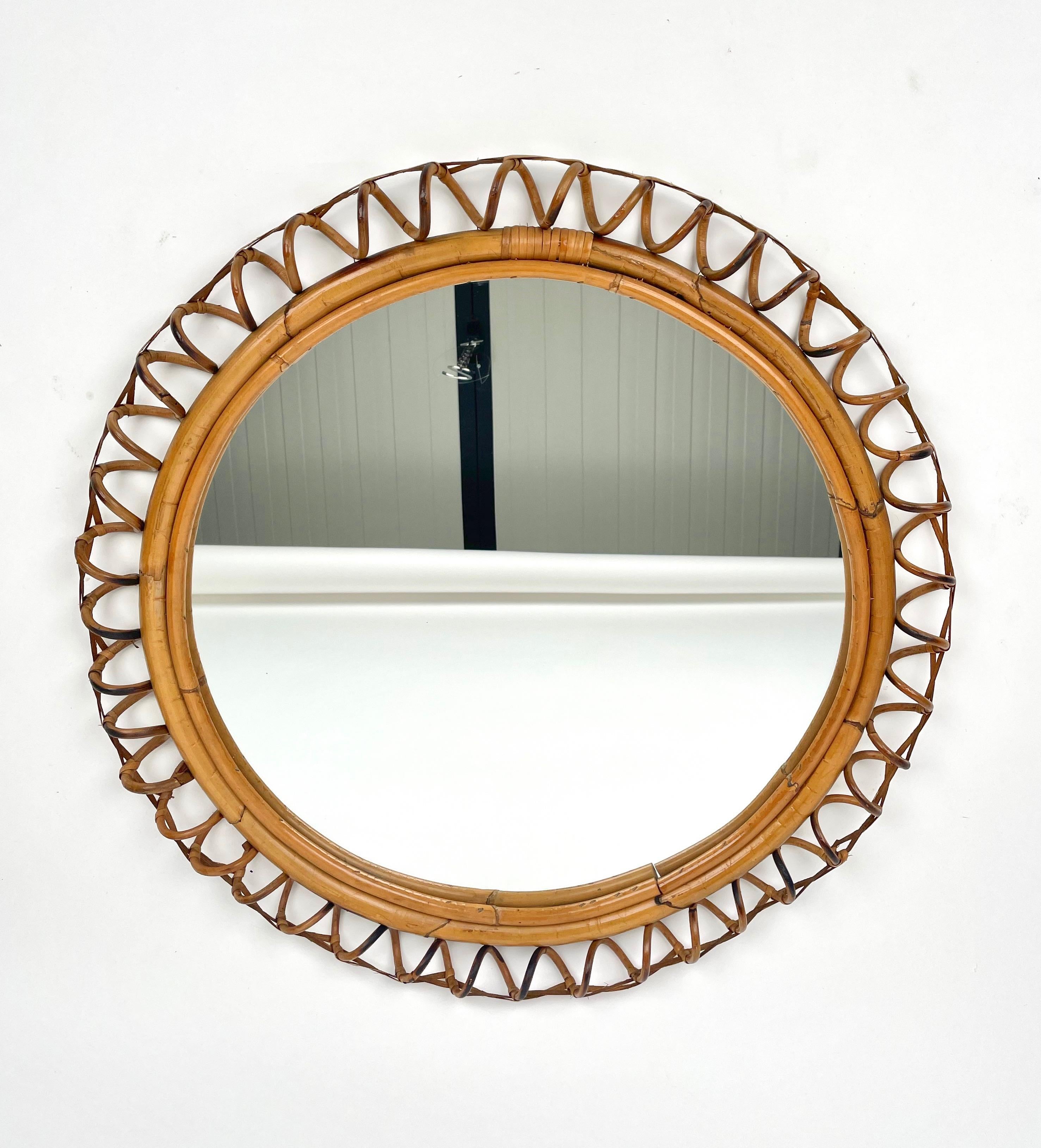 1960s Italian round wall mirror in rattan and bamboo. The rattan is woven as an elegant spiral surrounded by a rattan strip and the mirror is framed by two bamboo pieces.