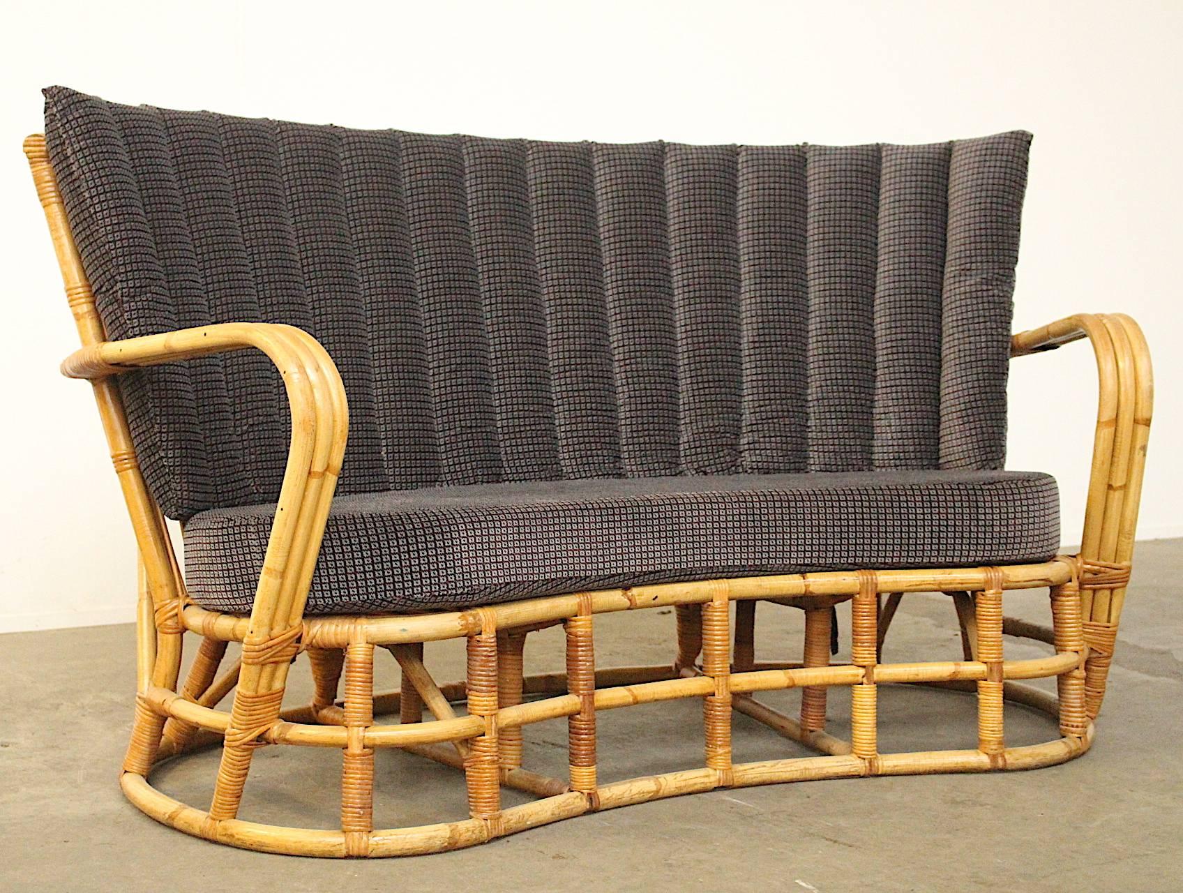 Stunning rattan sofa or settee in the style of Giovanni Travasa. The sofa has beautiful organic curves and a wonderfully handcrafted frame that holds two very comfortable thick foam cushions with a square S-patterned dark gray and black upholstery.