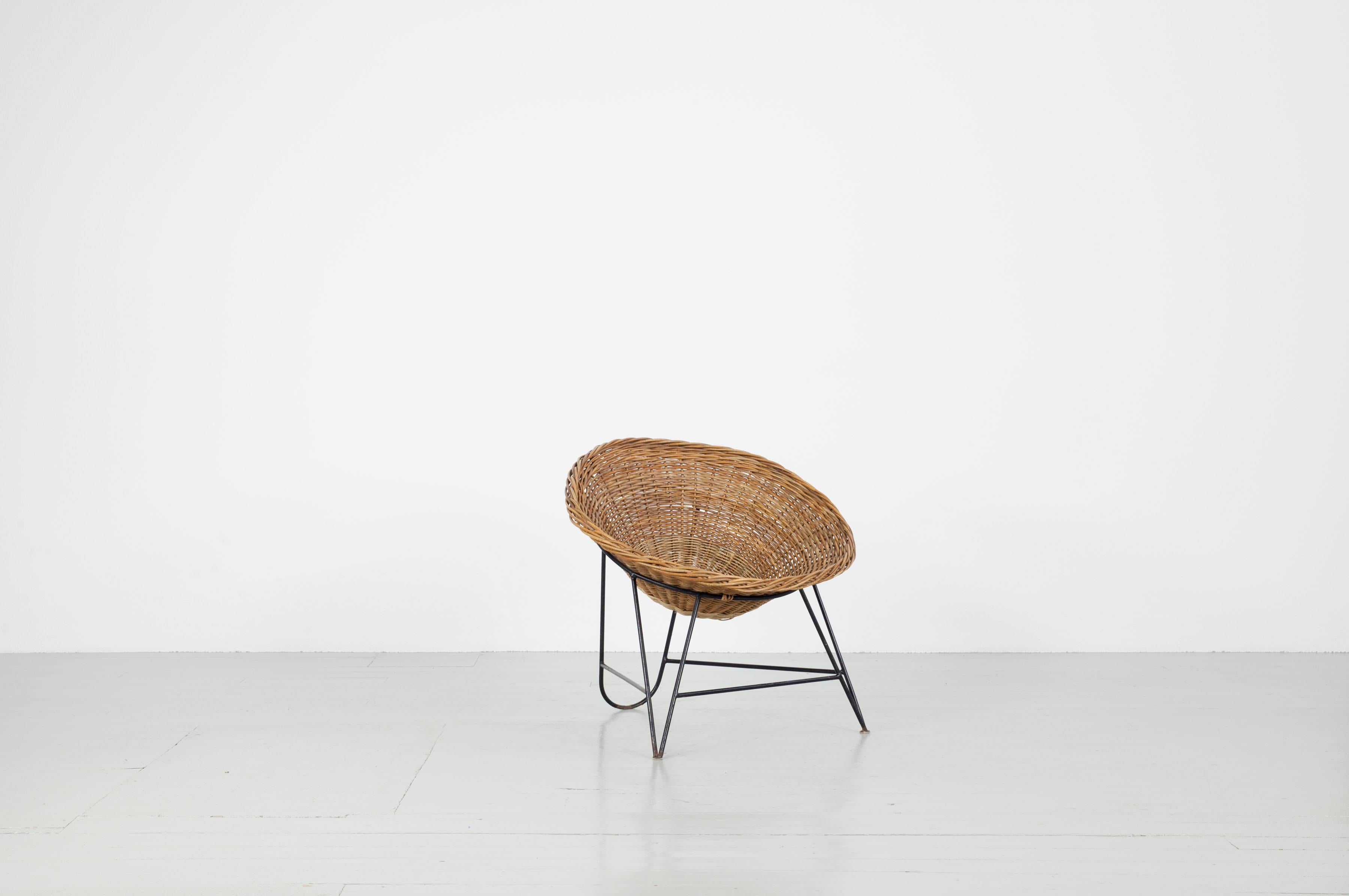 Rattan basket chair, Italy, 1950s. The chairs are often described as coconut-shaped. The feature a rattan seat shell and a base of lacquered iron.