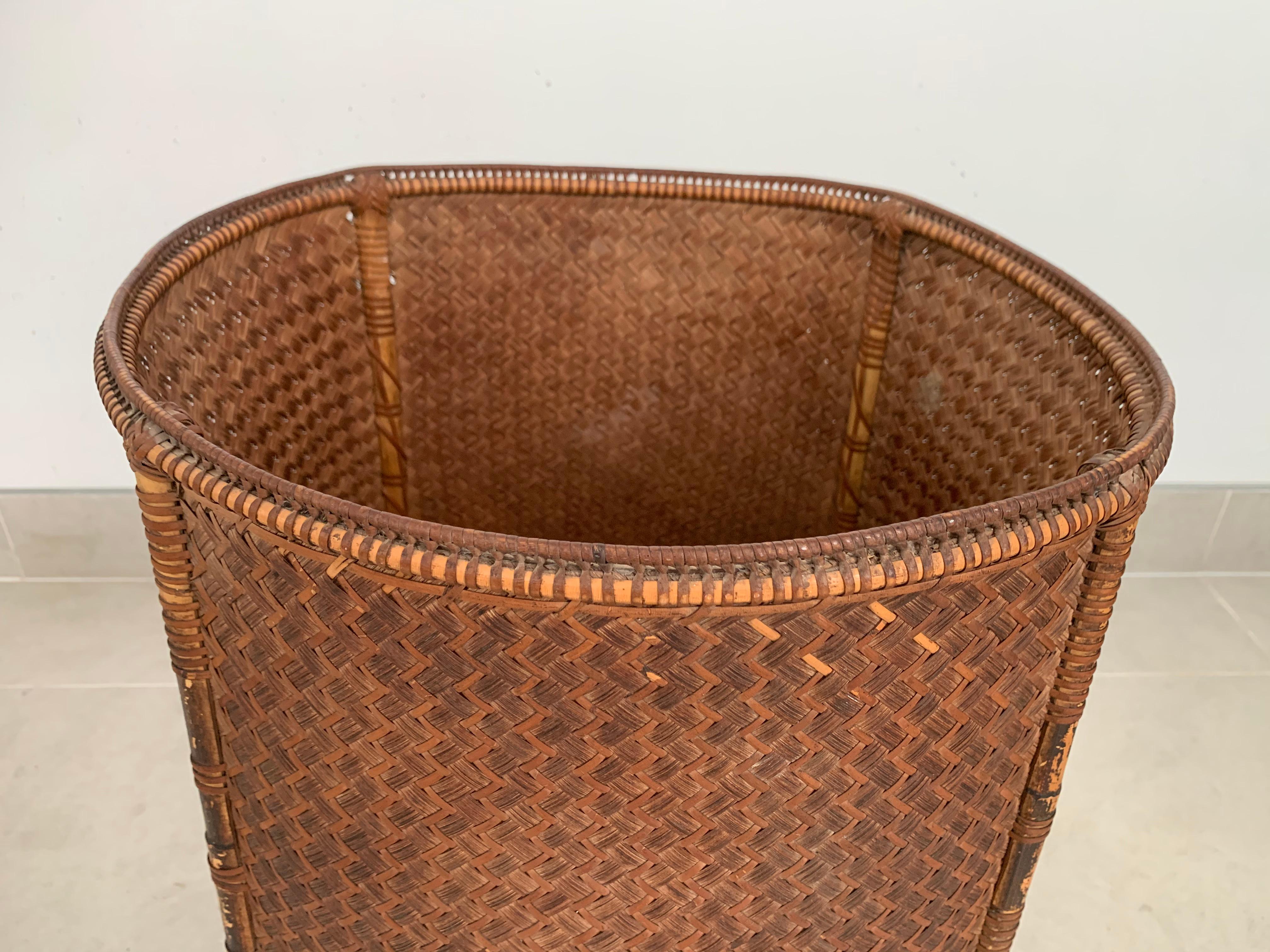 This mid-20th century hand-woven basket originates from the Dayak tribe of Borneo crafted with rattan fibres. These baskets were used to carry leaves, fruit, grain and wood and features wonderfully aged fibres and wood patina.

Measures: Height