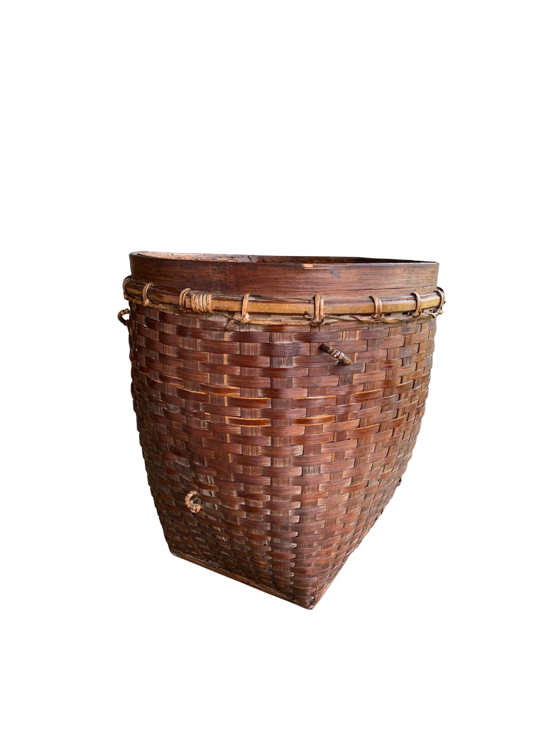 This mid-20th century hand-woven basket originates from the Dayak tribe of Borneo crafted with rattan fibres and an iron wood frame. These baskets were used to carry leaves, fruit, grain and wood and features wonderfully aged fibres and wood patina.