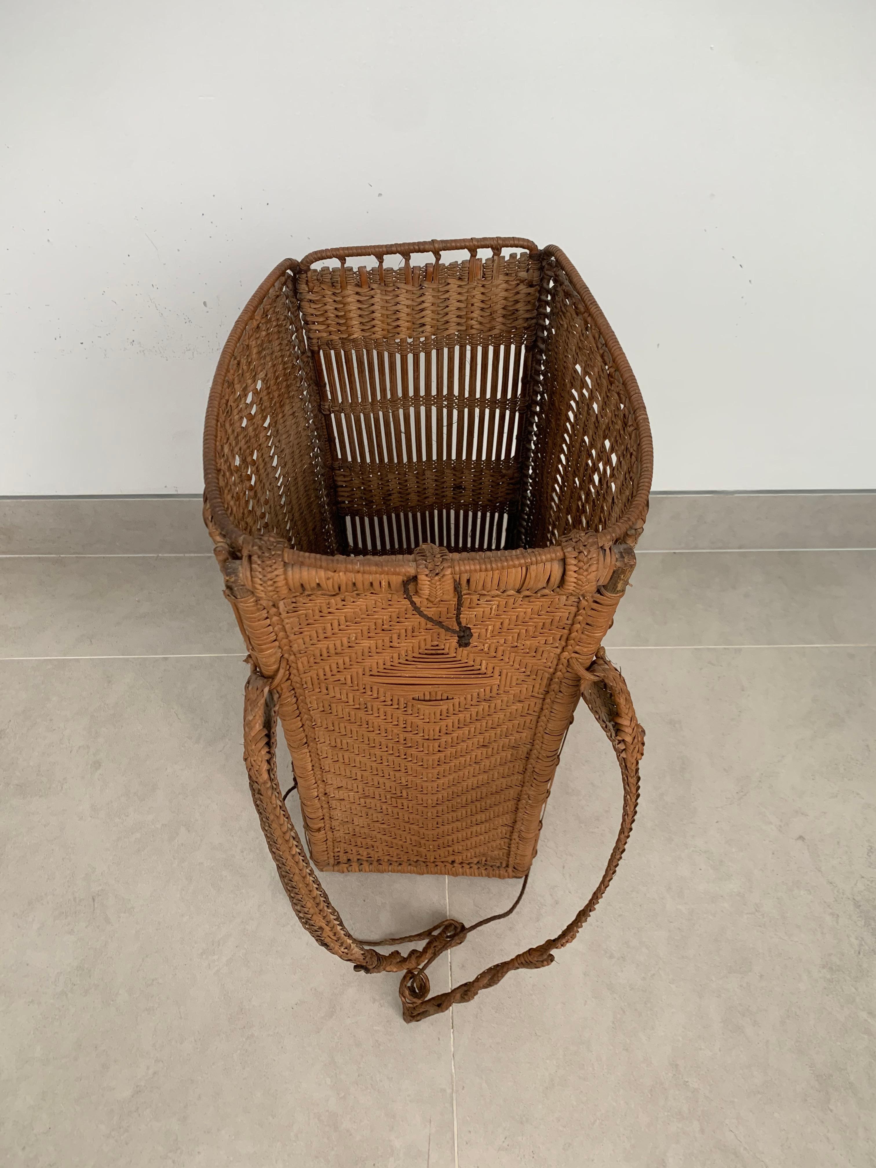 This mid-20th century hand-woven basket originates from the Dayak tribe of Borneo, crafted with rattan fibres. These baskets were used to carry leaves, fruit, grain and wood and features wonderfully aged fibres and wood patina. This basket has a