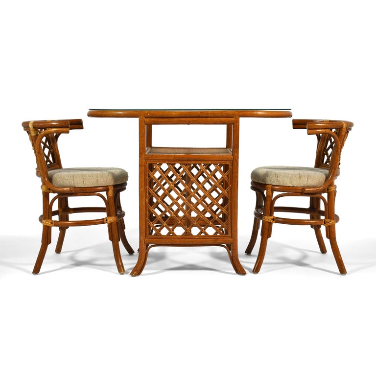 This lovely little rattan and cane set made in the late 1970s includes a small table with an oval glass top and two chairs that fit under the table, creating a compact footprint. Sometimes called a 