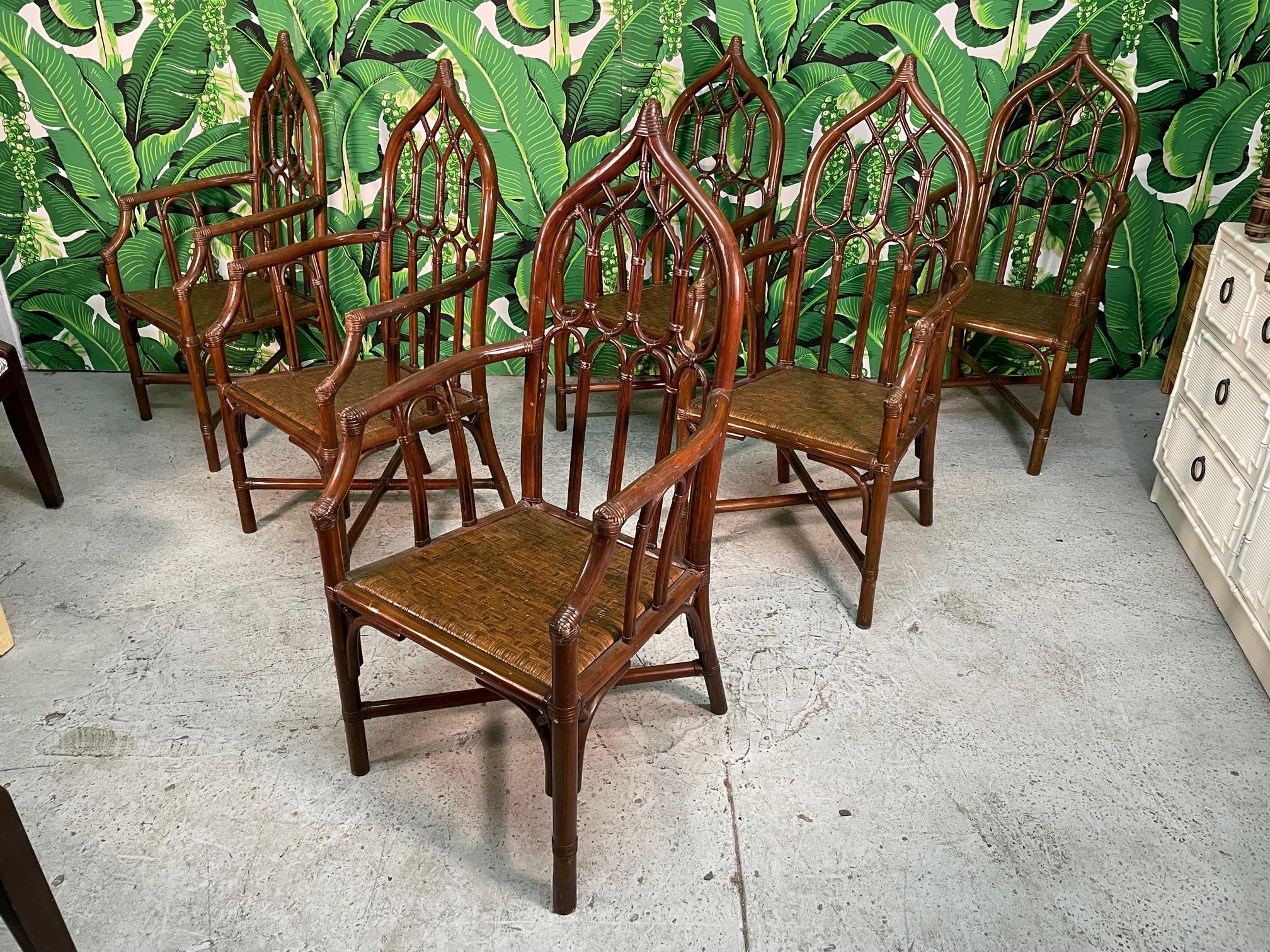 Set of six rattan dining chairs feature a cathedral style design in the manner of McGuire. Woven rattan seats and a deep, rich brown finish. Made by Rattan Originals in Cebu, Philippines. Good vintage condition with imperfections consistent with age