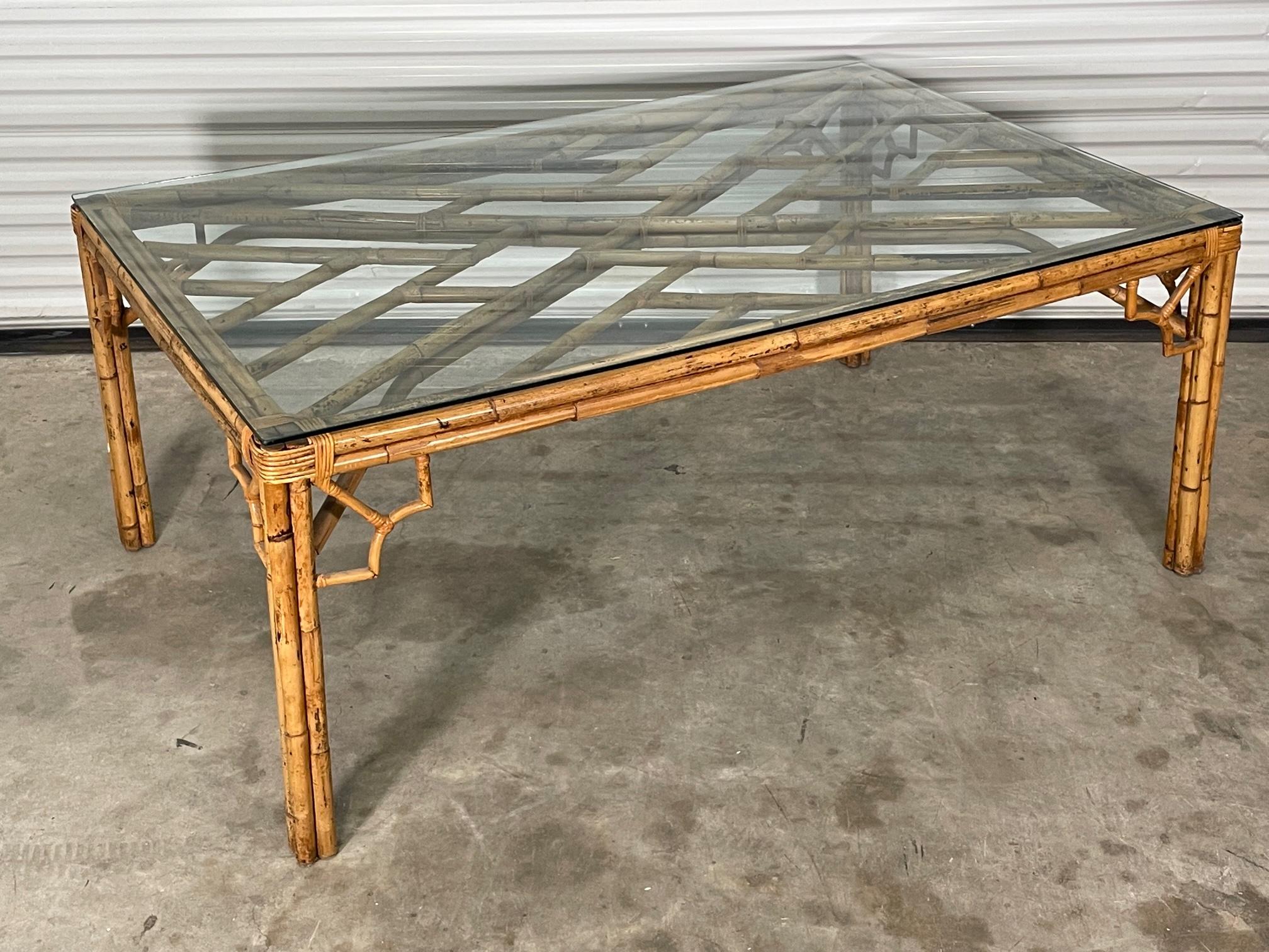 Rattan dining table features fretwork in an Asian chinoiserie design and glass top. Good condition with imperfections consistent with age. May exhibit scuffs, marks, or wear, see photos for details.

 