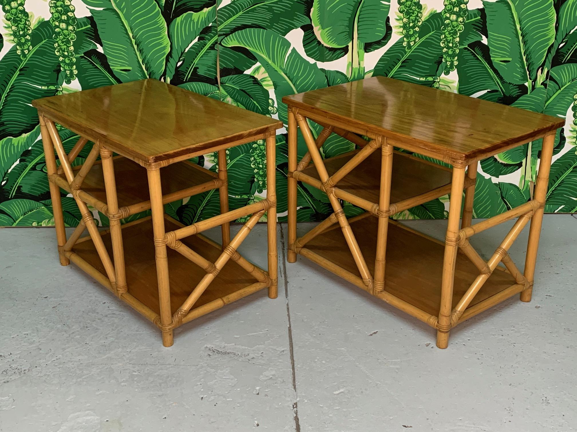 Pair of rattan side tables feature chinoiserie style detailing and solid wood shelves. Very good condition with only minor imperfections consistent with gentle use.  T2323