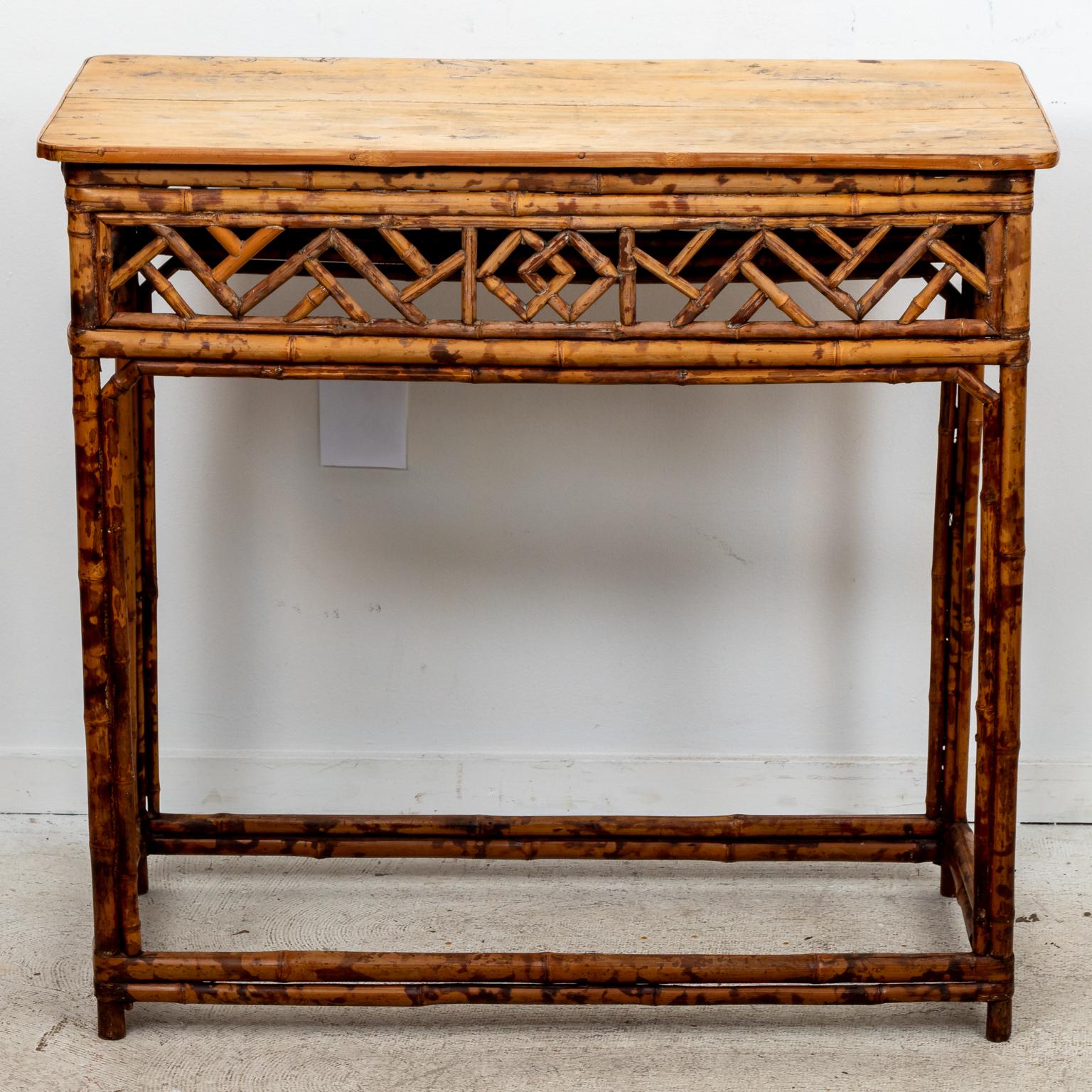 Circa 1960s Rattan console in the Mid-Century Modern style with open geometric fretwork panels on the table skirt and bottom stretchers. Please note of wear consistent with age including finish loss and chips to the rattan.