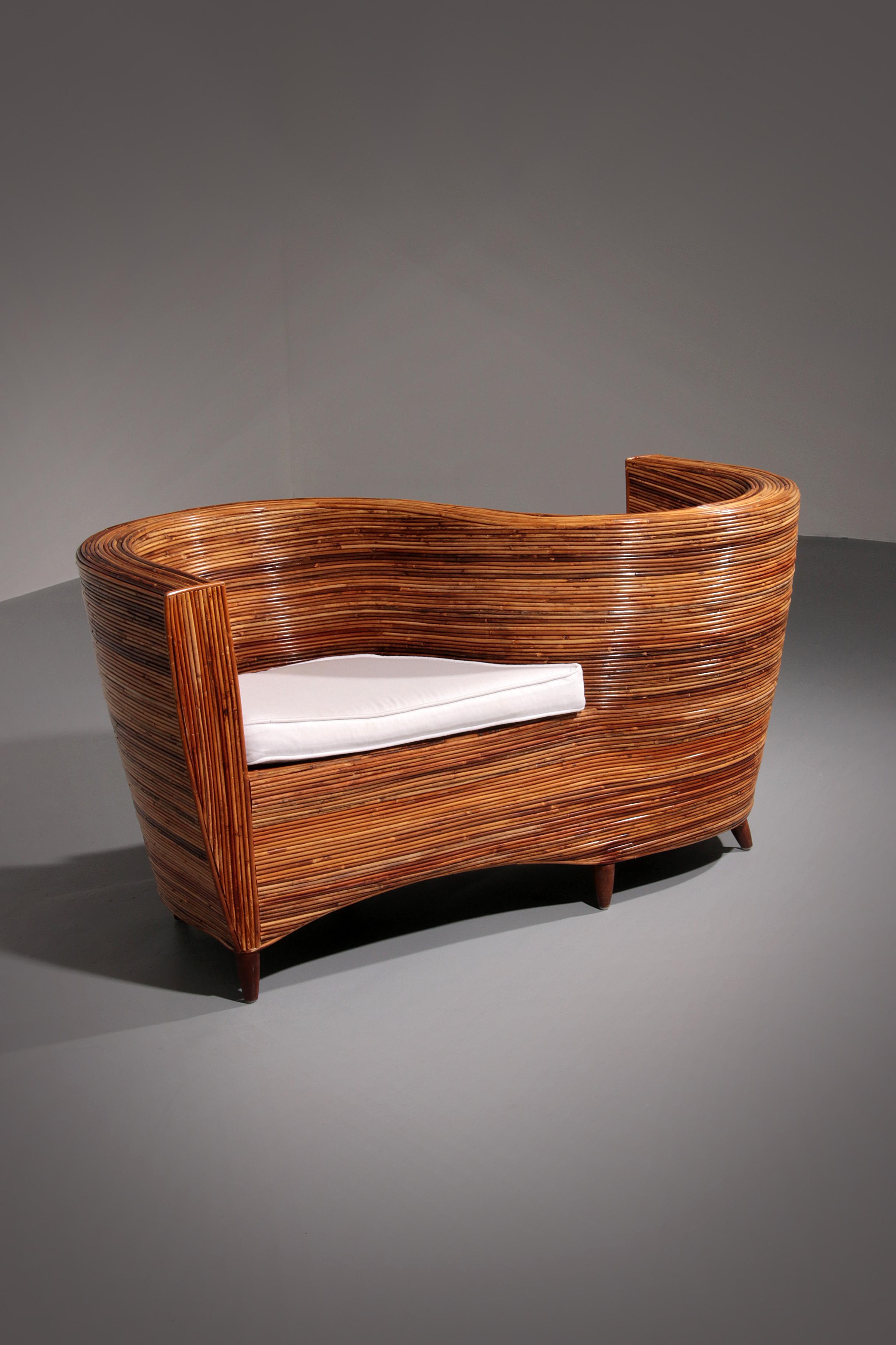 Handcrafted with exceptional skill, this striking rattan conversation chair from Vivai Del Sud showcases a flowing serpentine design that captivates from every angle. Designed in France in the 1980s, it seamlessly blends artistry and function,