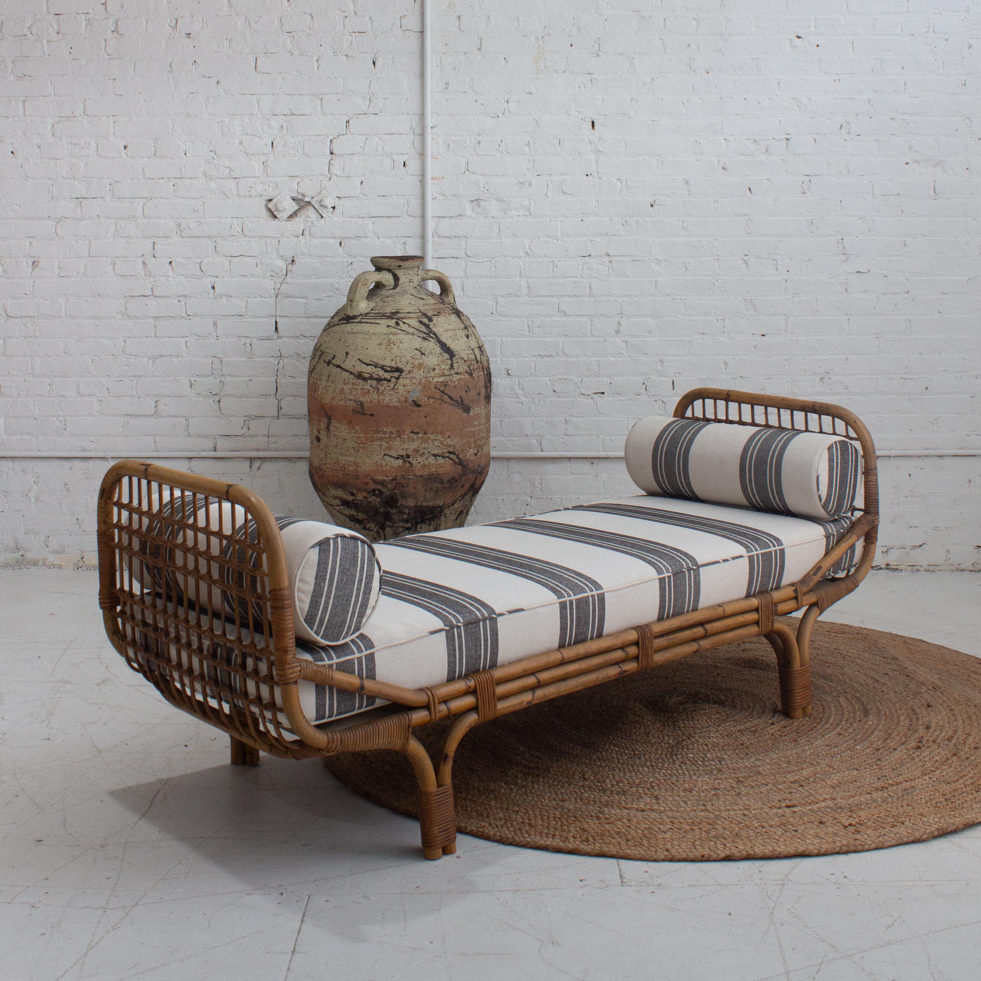 A rattan daybed by Tito Agnoli for Bonacina. Newly reupholstered in a striped linen cotton blend with new foam and bolster pillows. New base decking added for support. Sourced in Northern Italy.