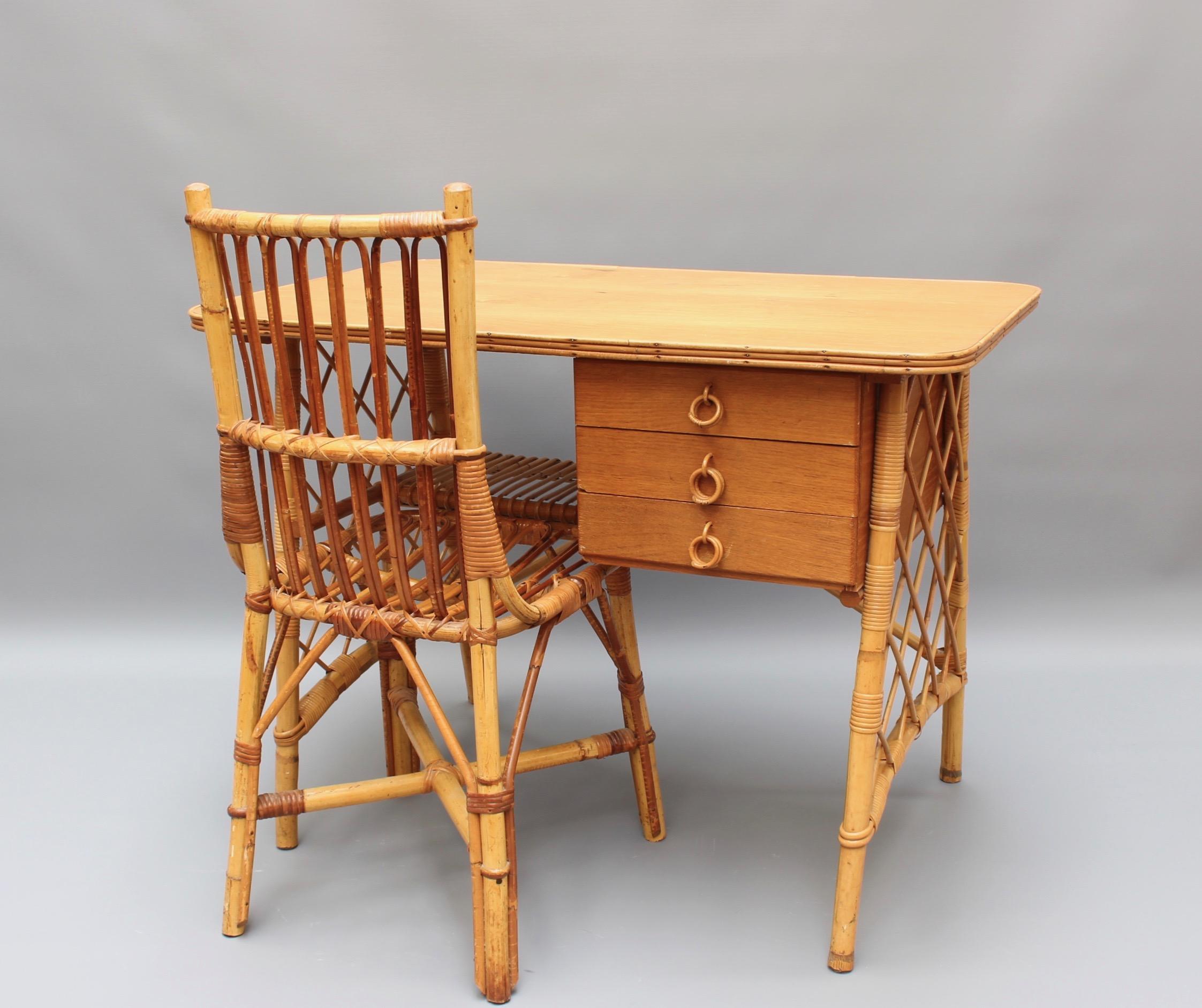 Rattan desk or vanity table and chair set by Louis Sognot (circa 1950s). Characteristic of its period, there are three drawers located under this rattan desk as well as a storage shelf. Rattan grilled panels connect the side legs. The desktop is