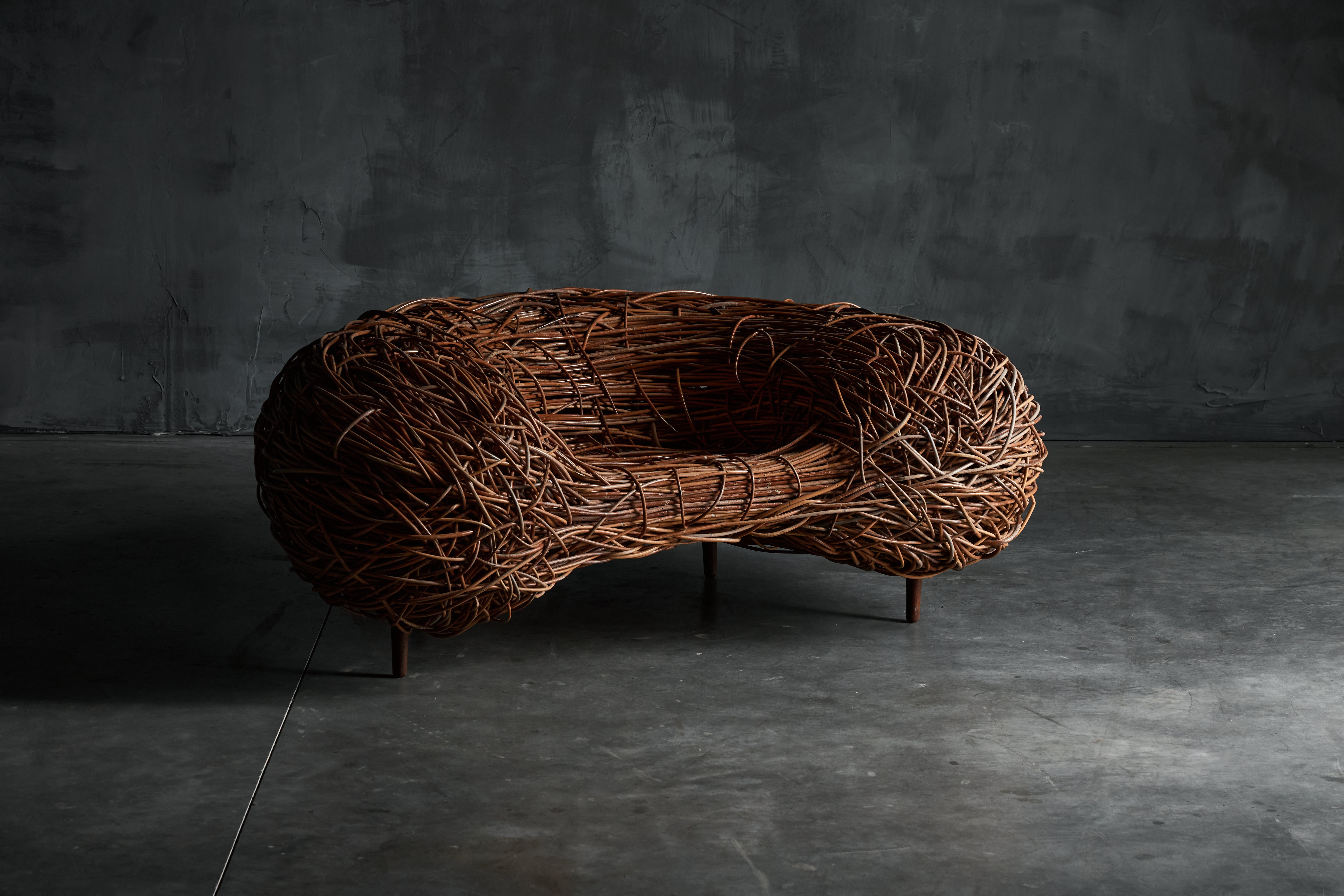 Bird's Nest Easy Chair aus Rattan, ein Meisterwerk, das dem visionären Designer Porky Hefer zugeschrieben wird. Hefer hat sich von der Weisheit der Natur inspirieren lassen und die Wabi-Sabi-Prinzipien nahtlos in diese Kreation einfließen lassen, um