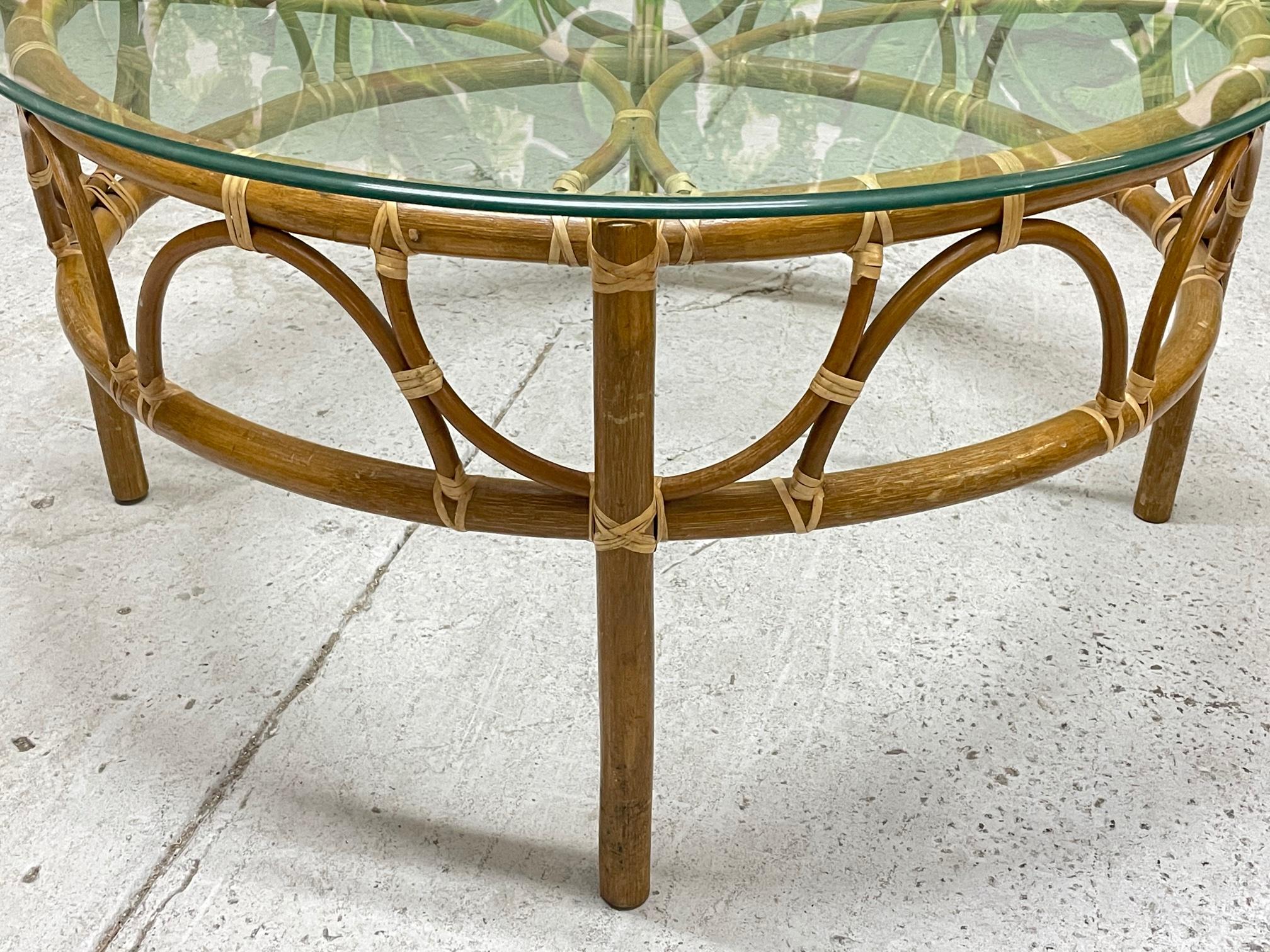 Vintage rattan coffee table in boho style with a glass round top. Good condition with minor imperfections consistent with age.