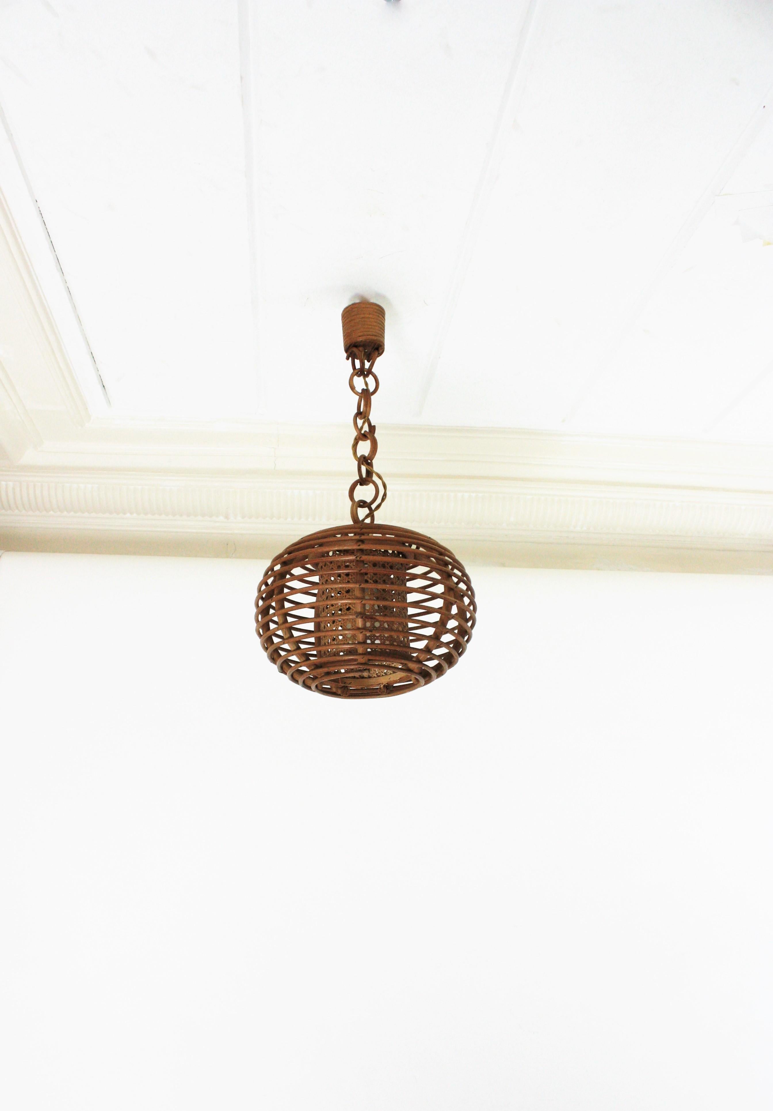 Eye-catching rattan lantern with globe or ball shaped lampshade, Spain, 1950-1960s.
This suspension lamps is entirely handcrafted with rattan, bamboo and wicker. The ball shaped shade hang from a chain with round rattan links that can be shortened