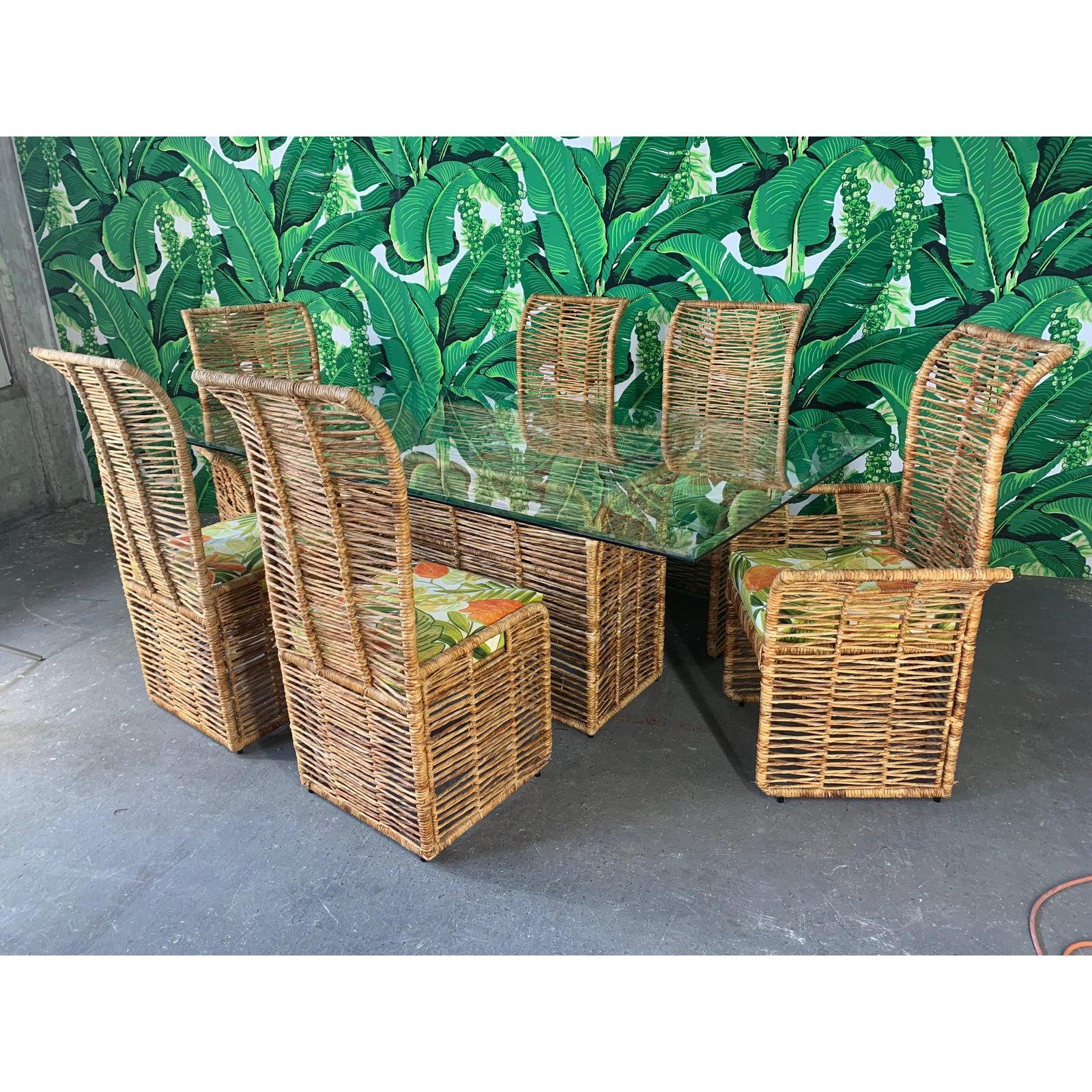 Unique dining set consists of 6 rattan rope wrapped dining chairs upholstered in a tropical palm leaf print and matching pedestal table with glass top. Steel frame construction, heavy and sturdy. Two arm chairs and four side chairs. Good vintage