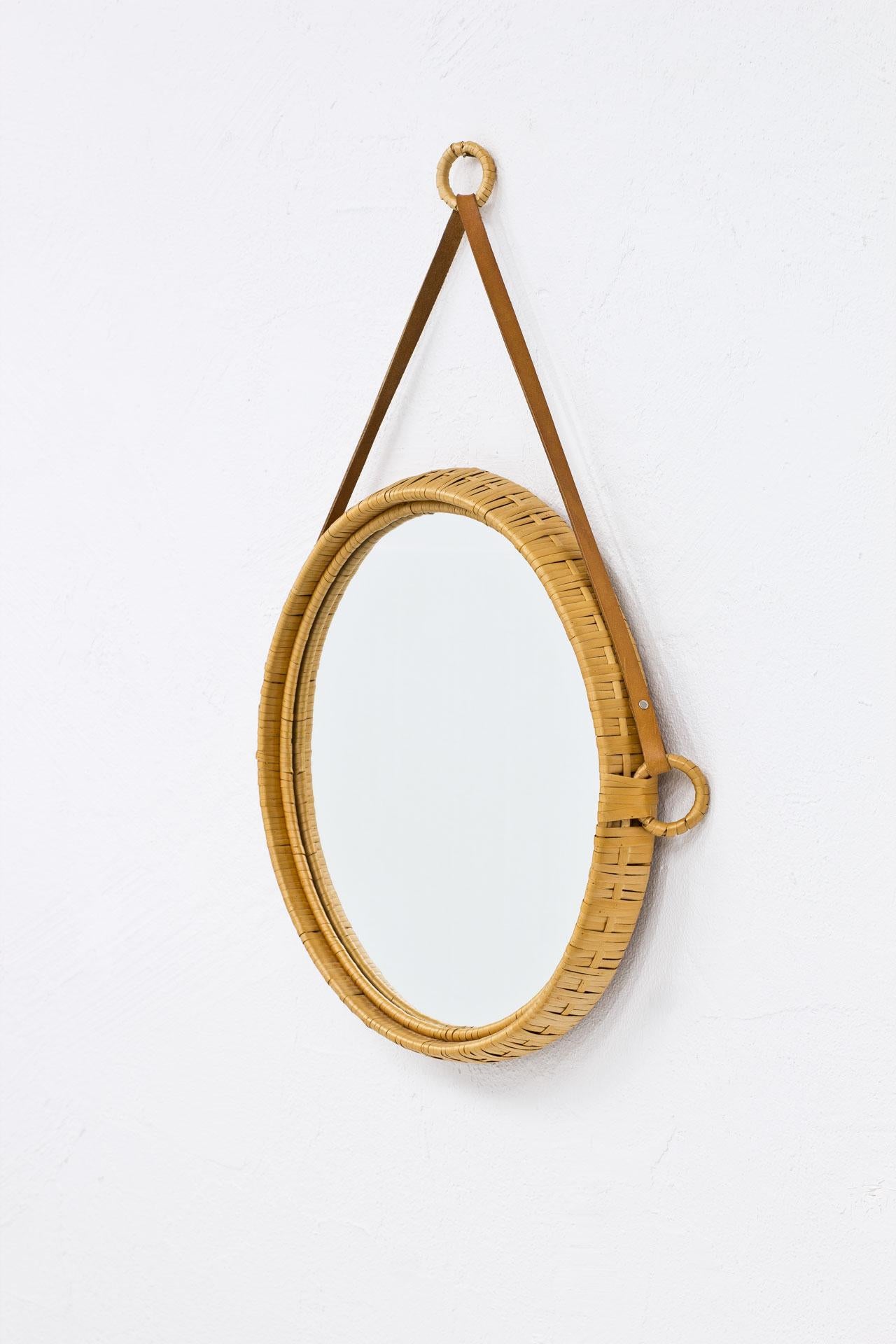 Round wall mirror, made from rattan with leather strap. Manufactured in Sweden during the 1960s by unknown maker.