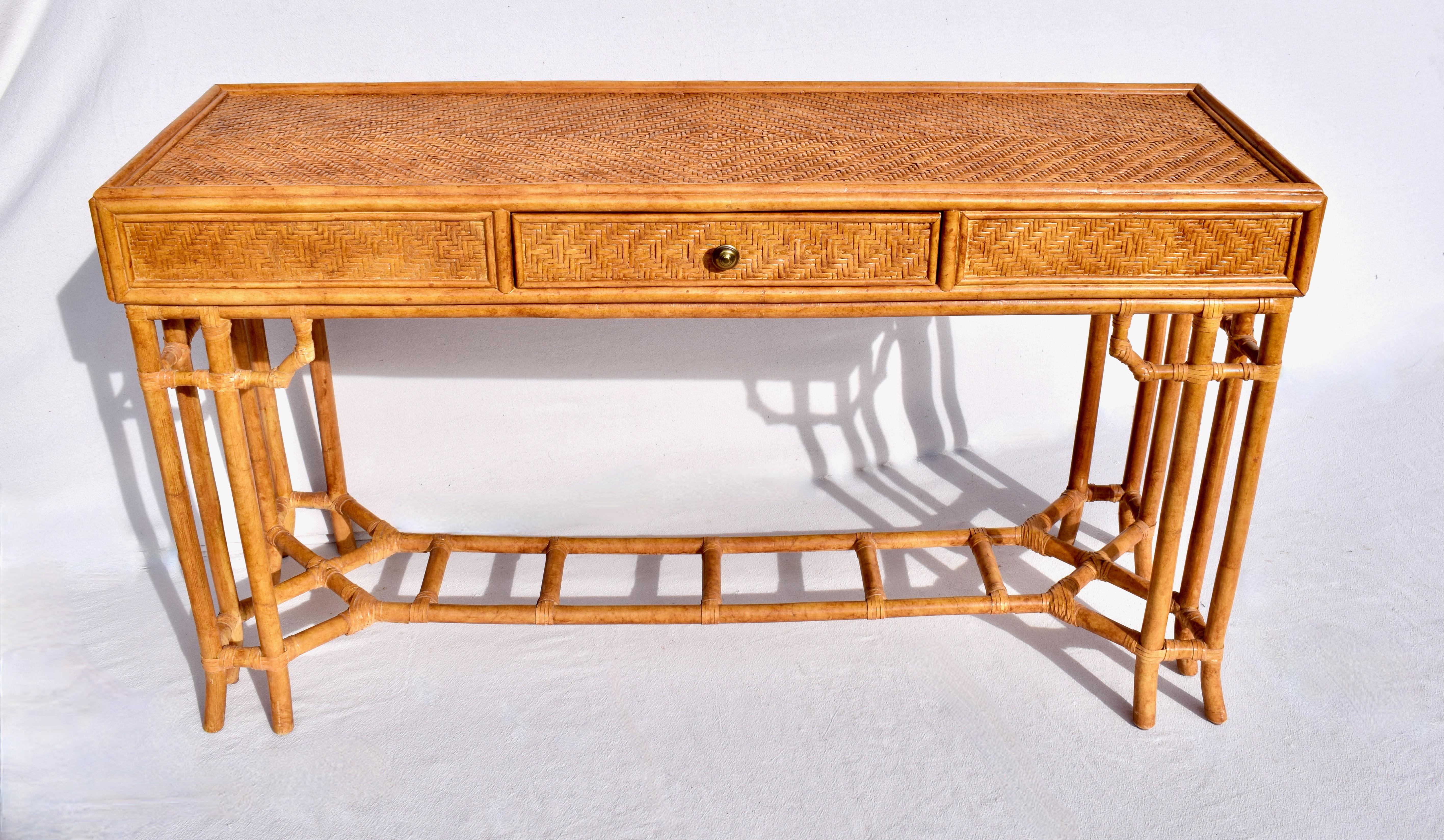 midcentury British Colonial Campaign style single drawer console or work table with distinct Chinese Chippendale design elements. Bamboo frame construction wrapped in woven cane rattan grass cloth & rawhide leather joinery features generous work