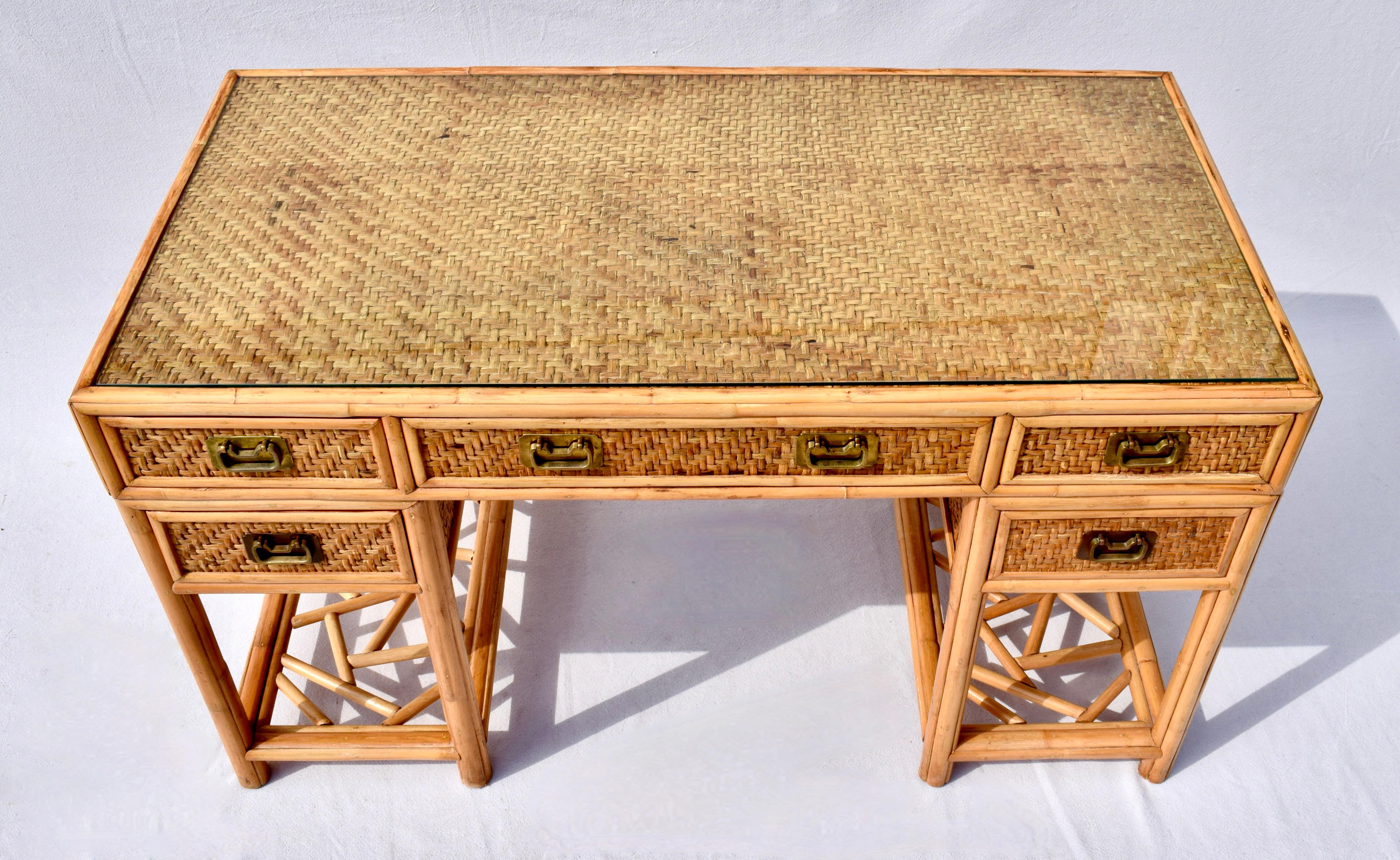 Midcentury British Colonial Campaign style 5-drawer writing desk or work table with distinct Chinese Chippendale design elements. Marvelous bamboo frame construction wrapped in woven basket weave cane rattan features generous work surface and custom