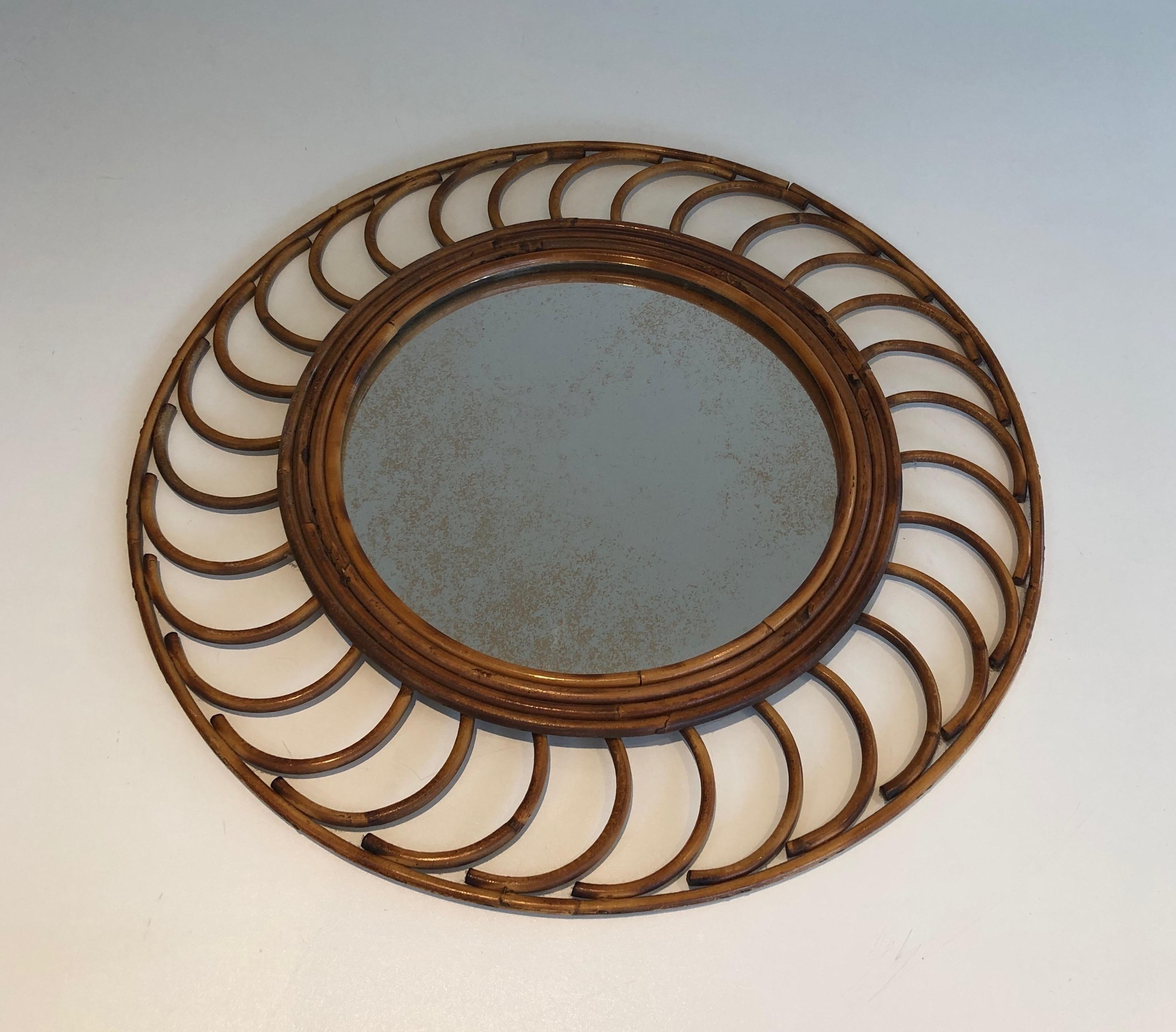 Ce joli miroir rond est fabriqué en rotin. Il s'agit d'une œuvre française. circa 1970.